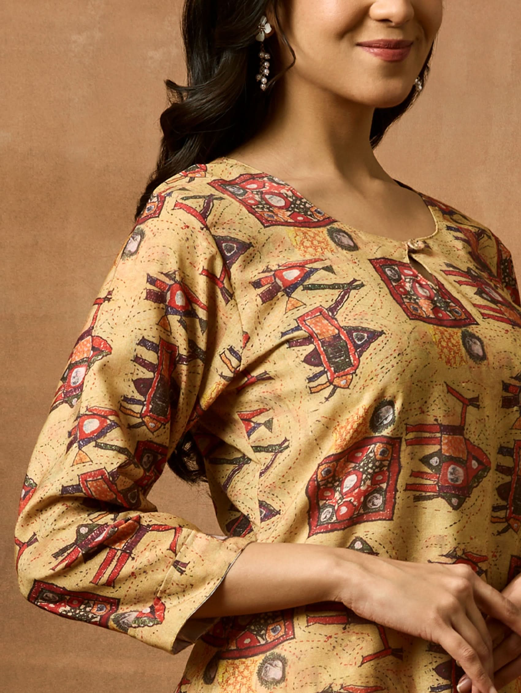A woman plus size model wearing a beige and red printed viscose rayon kurta with round neckline, three-fourth sleeves, and side slits.