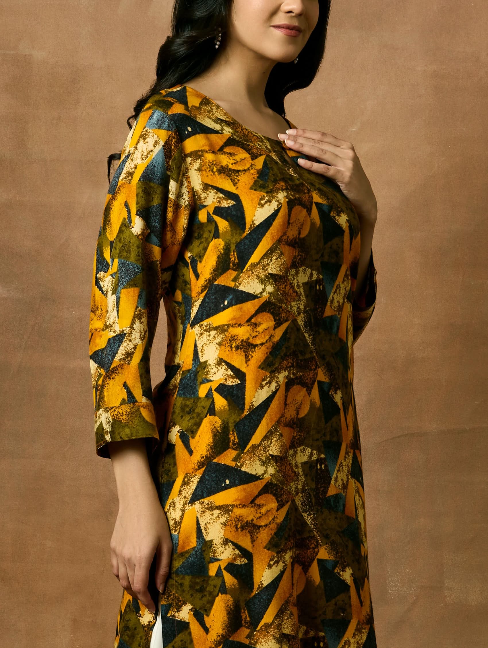 A woman plus size model wearing a printed viscose rayon kurta with a keyhole round neckline, three-fourth sleeves, and side slits.