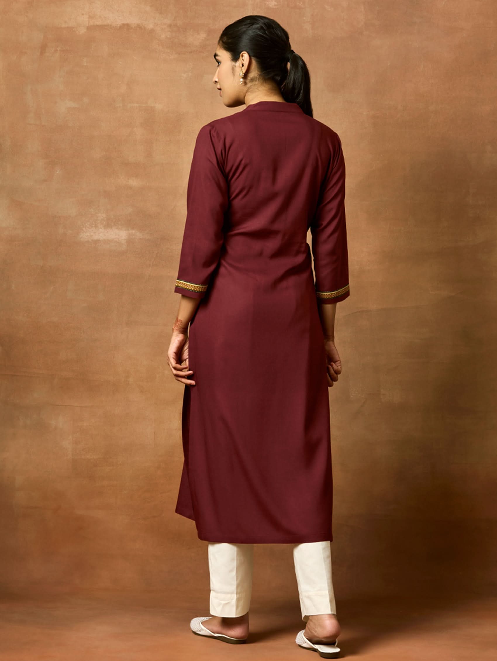 A woman plus-size model wearing a maroon viscose rayon kurta with a ban collar, three-fourth sleeves, and side slits. plain back