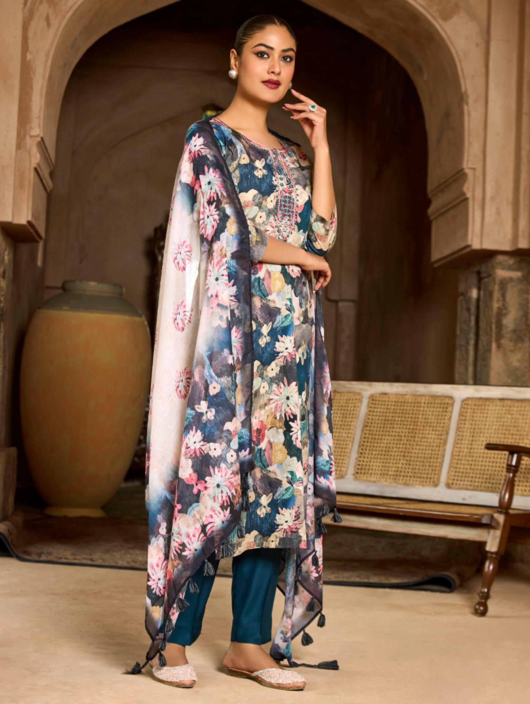 A woman wearing a floral malai cotton suit set with embroidered details,and printed consisting of a kurta, pants, and a printed weave silk dupatta.