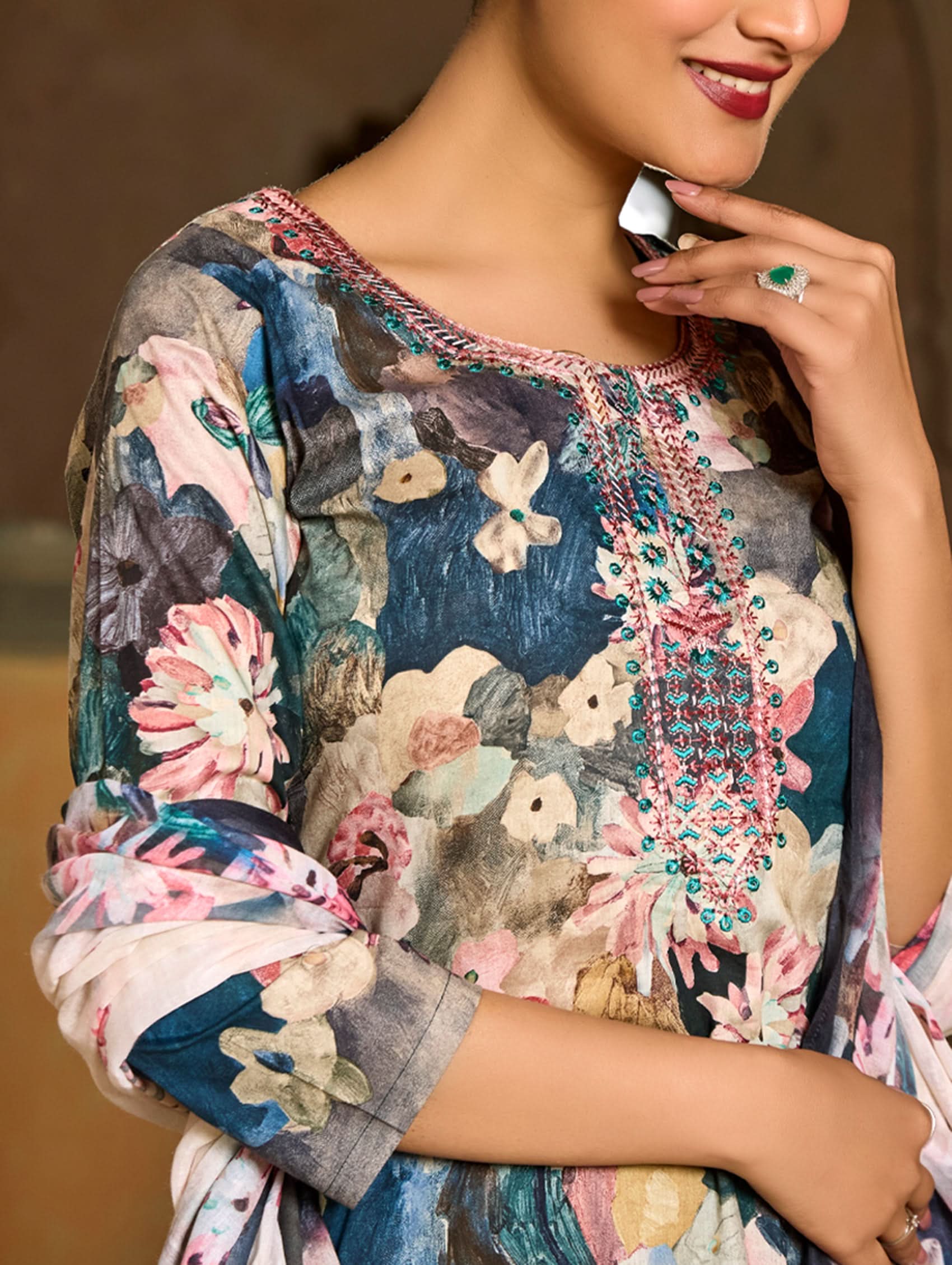A woman wearing a floral malai cotton suit set with embroidered details,and printed consisting of a kurta, pants, and a printed weave silk dupatta.
