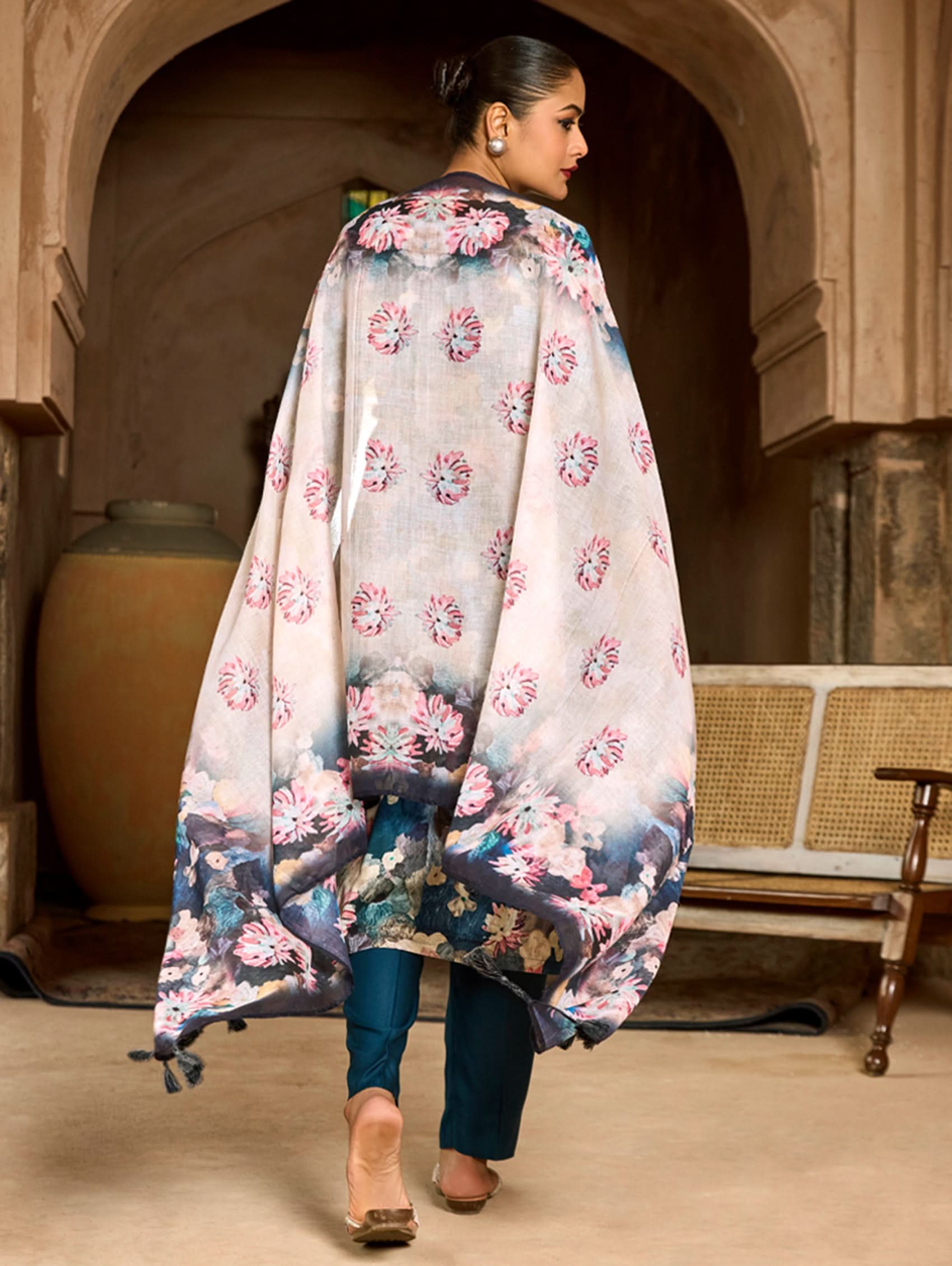 A woman wearing a floral malai cotton suit set with embroidered details,and printed consisting of a kurta, pants, and a printed weave silk dupatta.