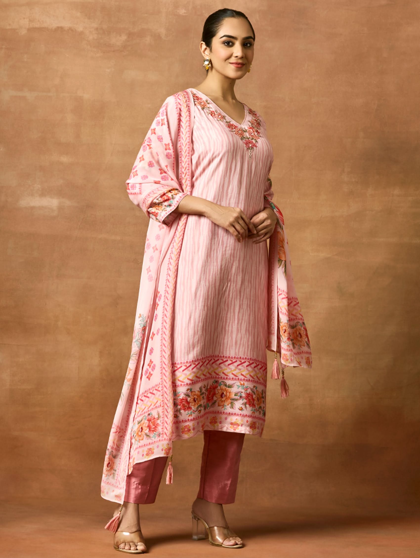 A woman modeling a pink and red digitally printed pure viscose muslin silk suit set with a kurta, pants, and a dupatta.