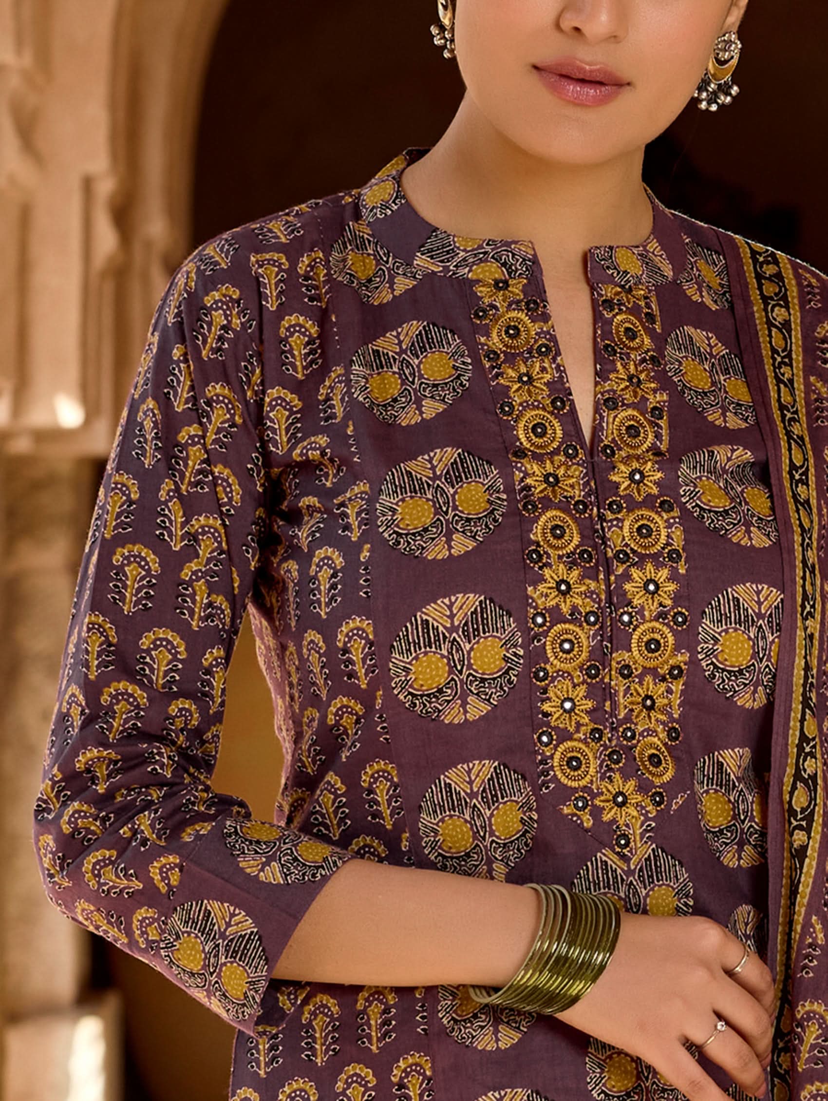 A woman wearing a purple and multicolored embroidered pure cotton suit set with a kurta, pants, and a dupatta.