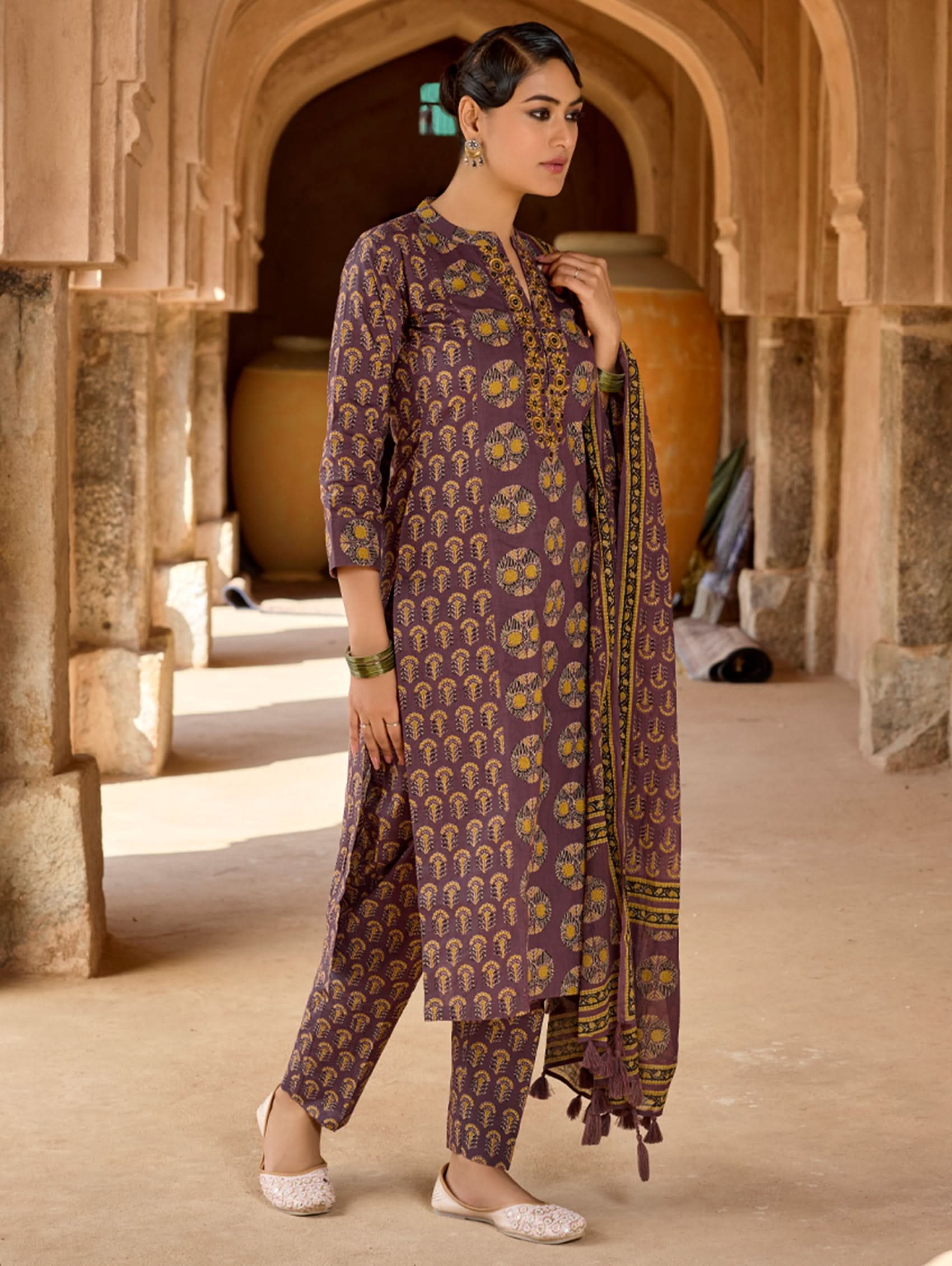 A woman wearing a purple and multicolored embroidered pure cotton suit set with a kurta, pants, and a dupatta.