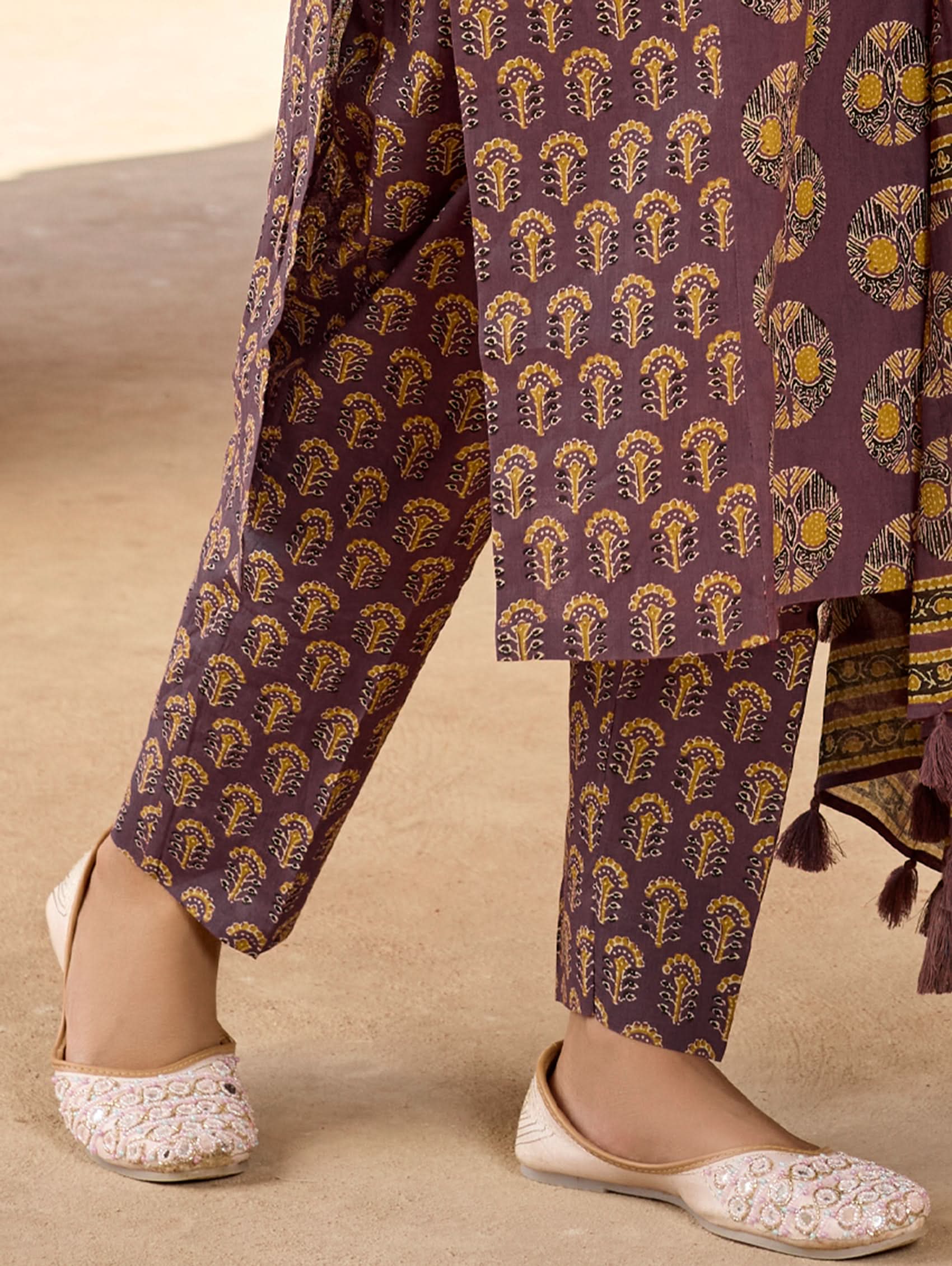A woman wearing a purple and multicolored embroidered pure cotton suit set with a kurta, pants, and a dupatta.