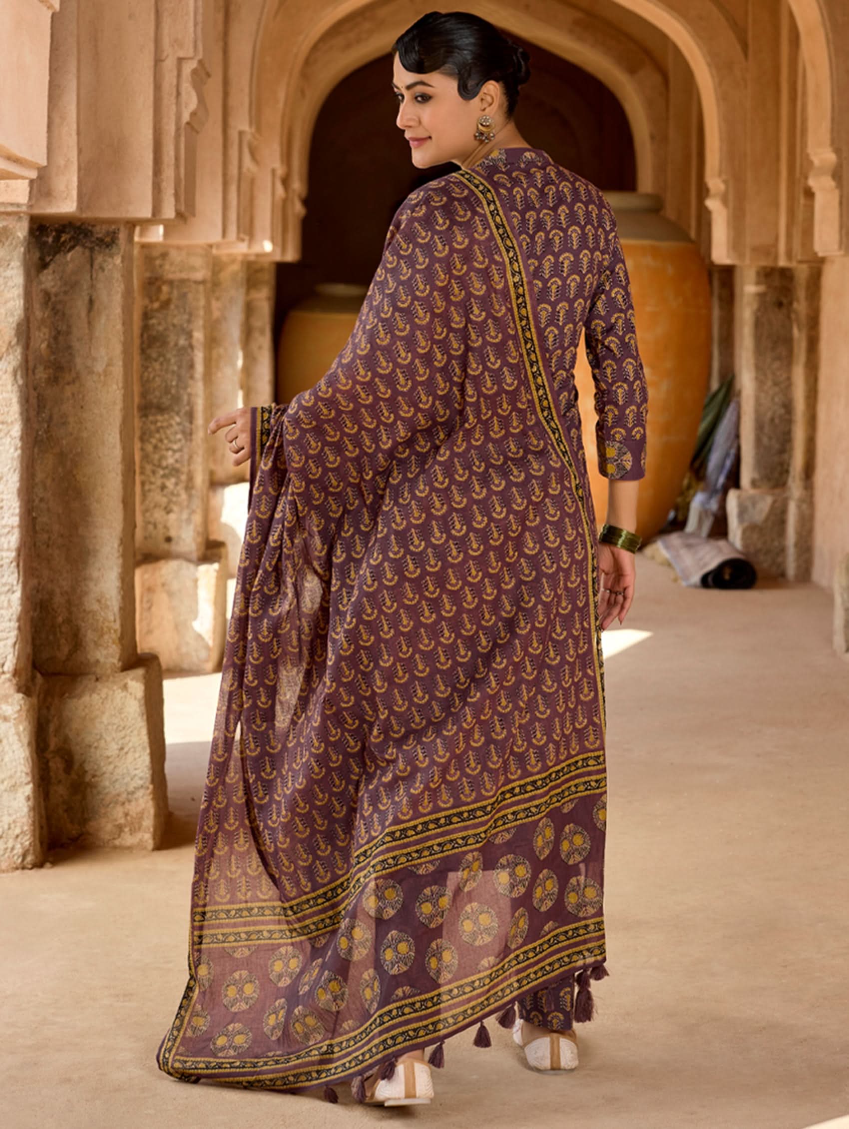 A woman wearing a purple and multicolored embroidered pure cotton suit set with a kurta, pants, and a dupatta.