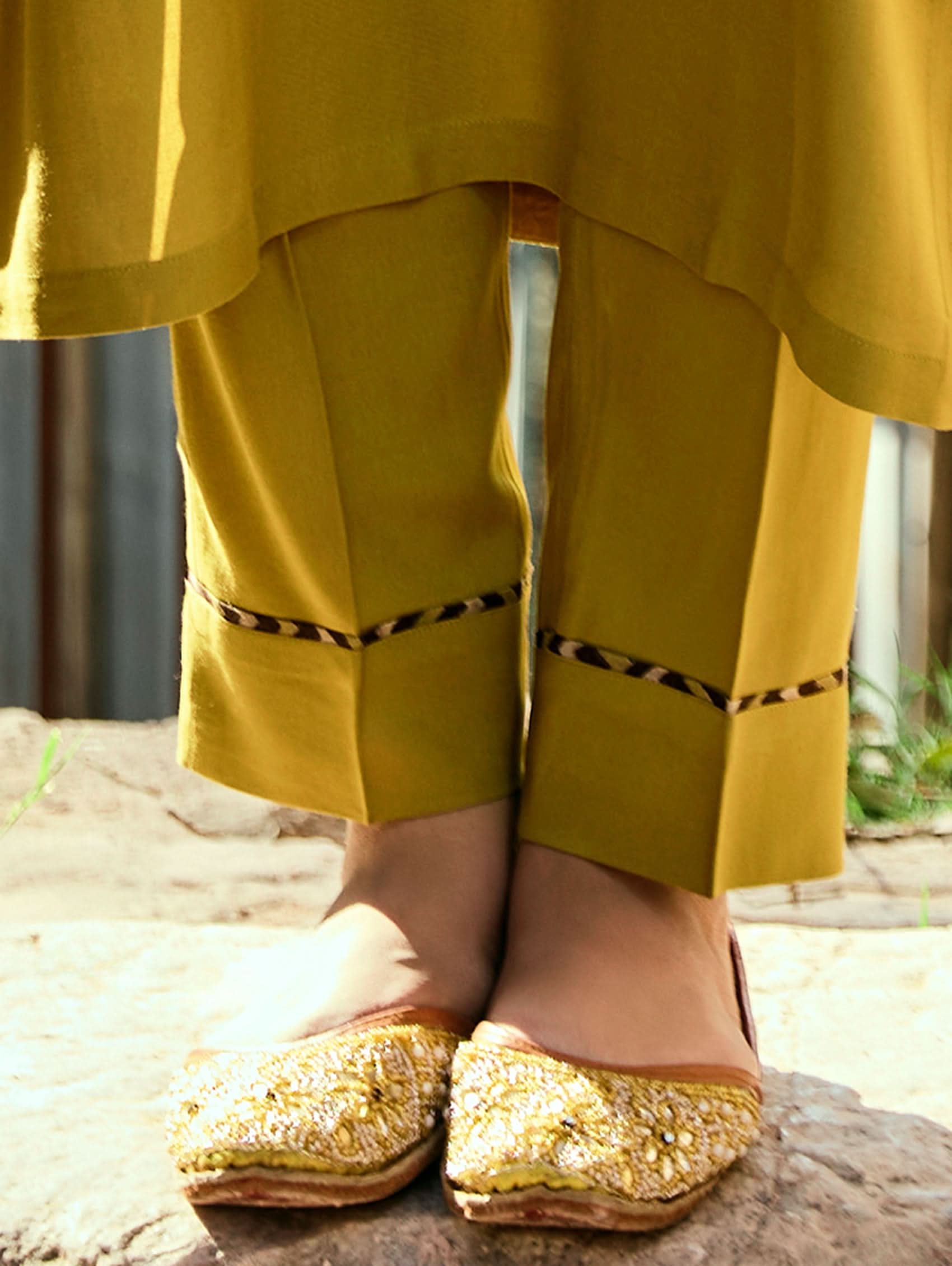 A woman wearing a yellow viscose rayon suit set with embroidery, including a kurta with three-fourth sleeves and a round neckline, pants with pockets, and a printed dupatta.