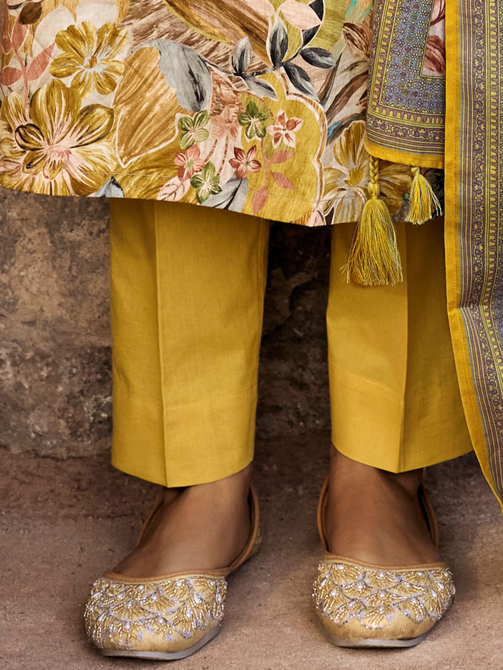 A woman wearing a yellow and multicolor embroidered pure malai cotton suit set with a kurta, pants, and a dupatta.