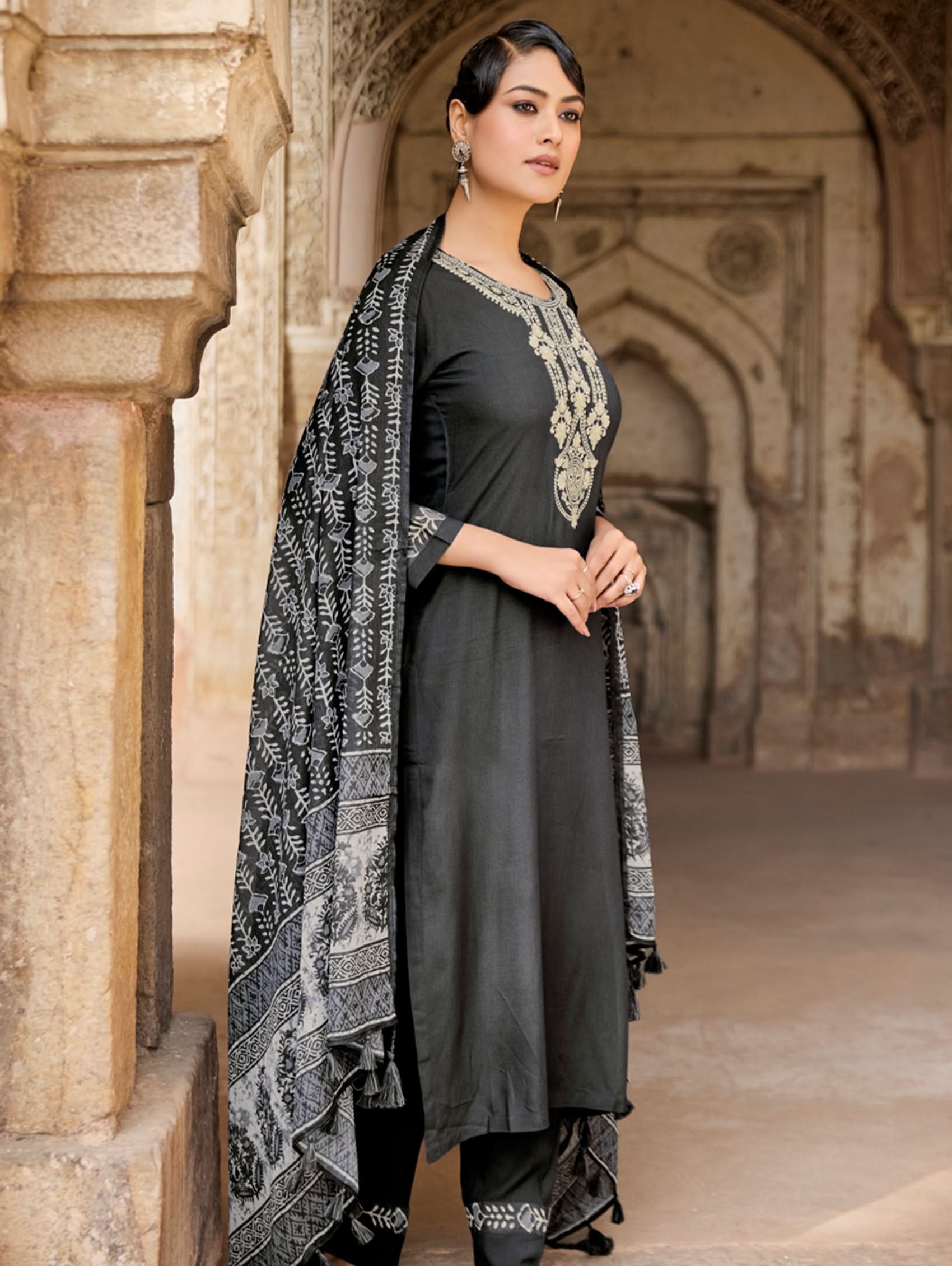 Woman in black traditional outfit with patterned shawl in an architectural setting