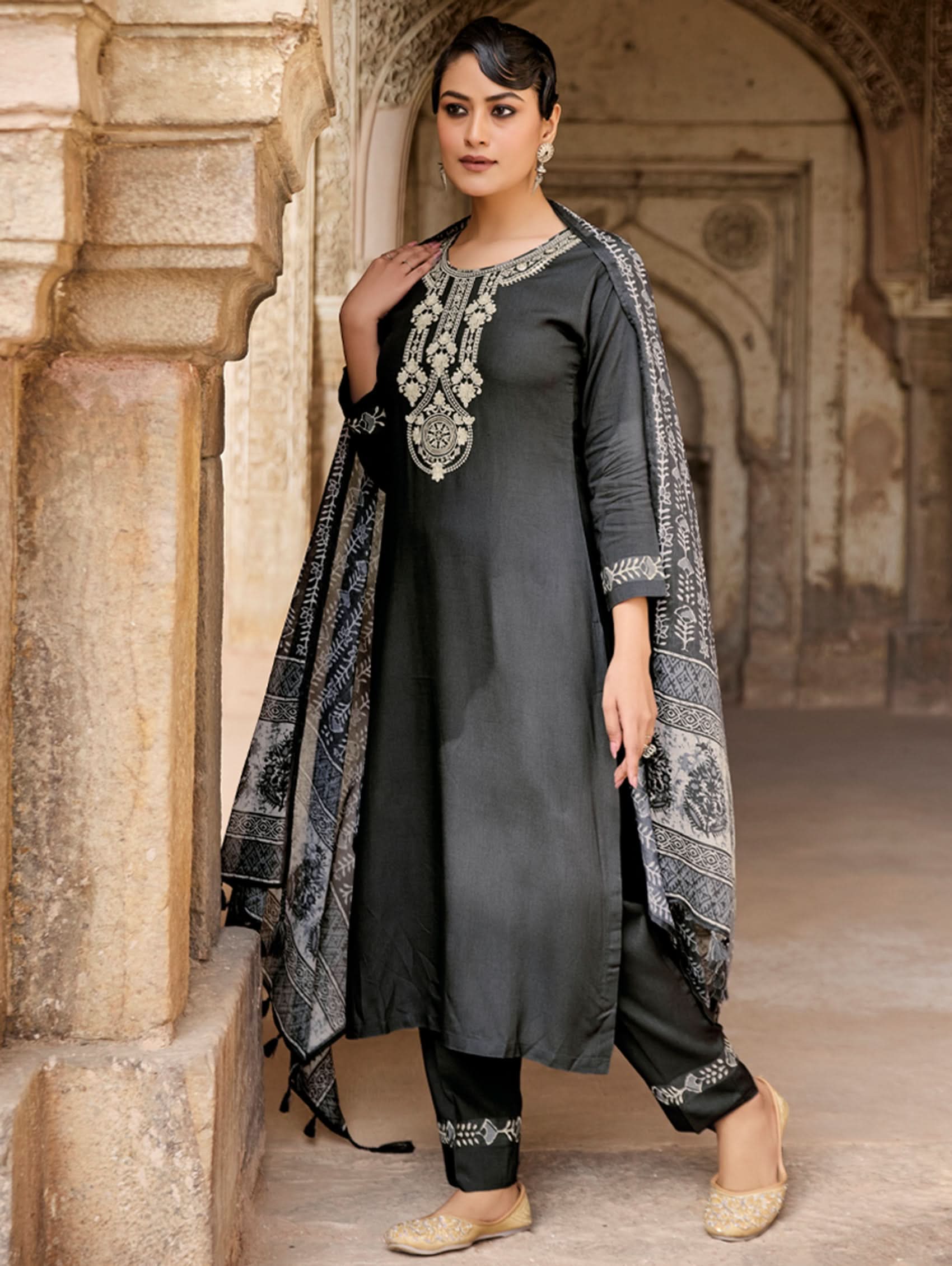Woman in black and silver traditional outfit standing in an archway.