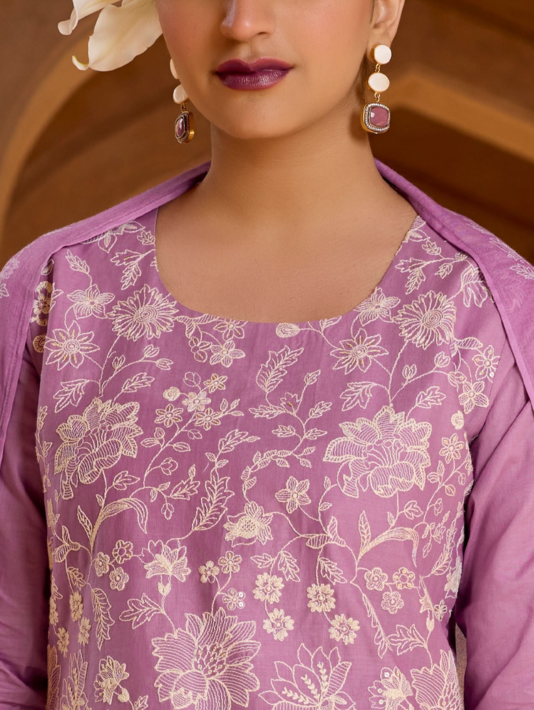 Close-up of a person wearing a purple floral garment with earrings.