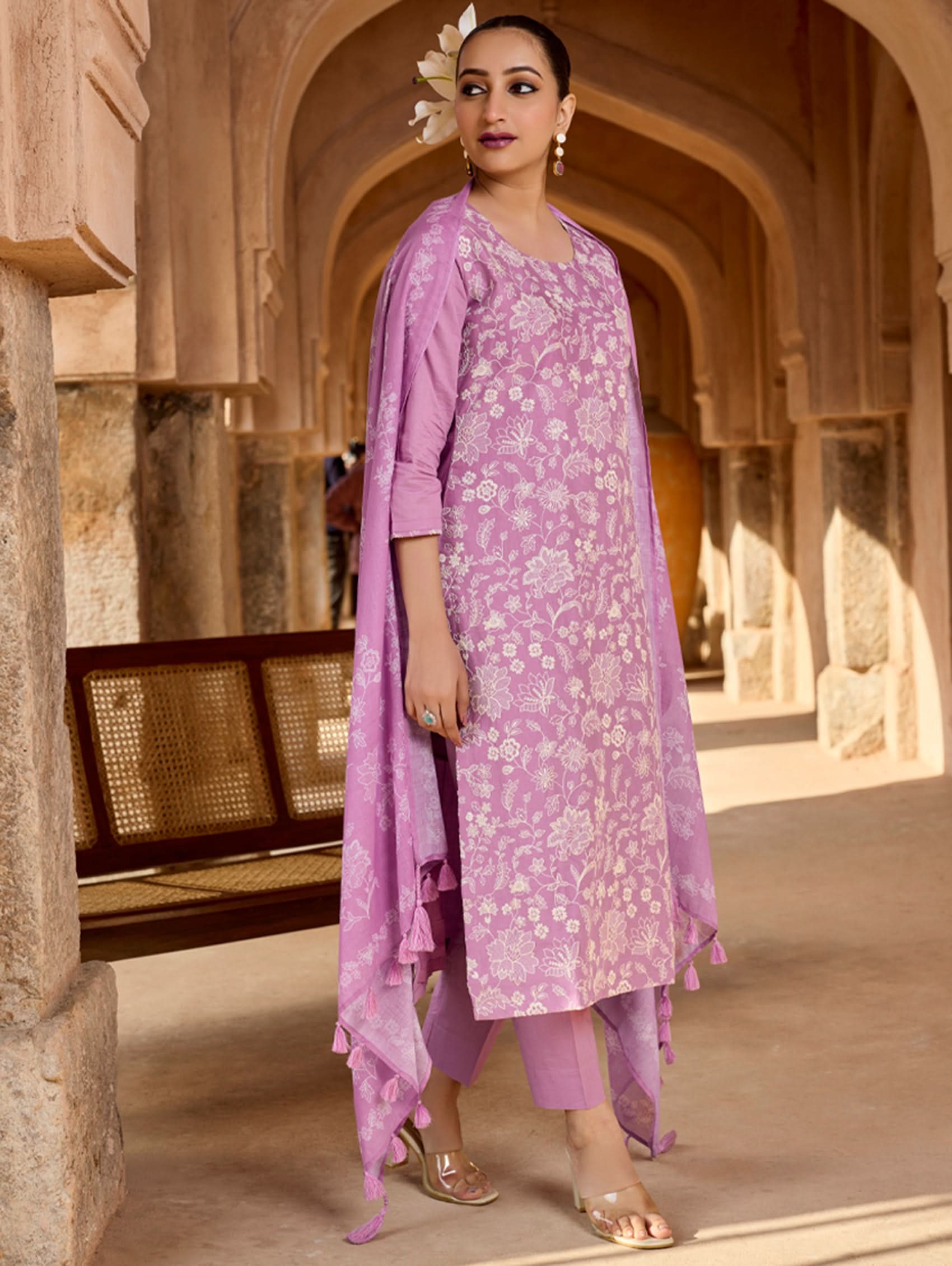 Woman in a purple traditional outfit standing in a architectural setting.