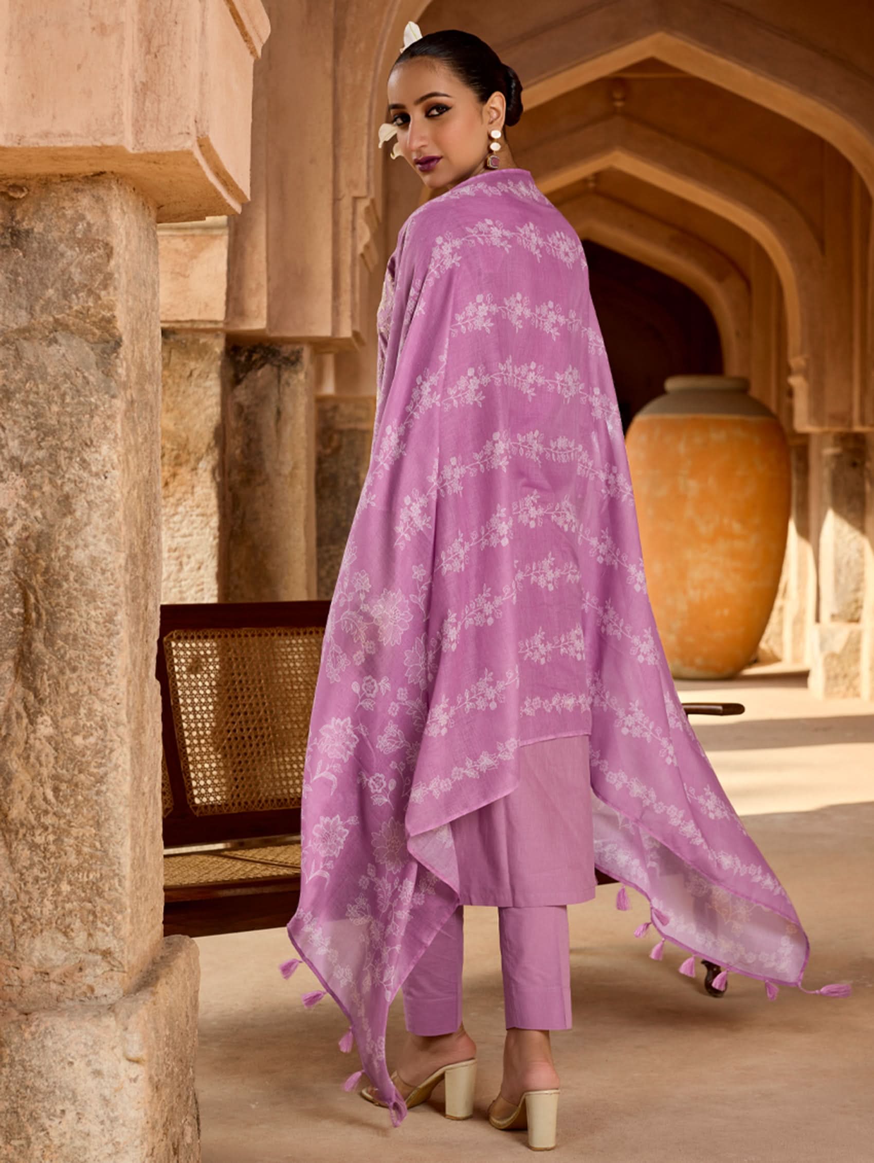 Woman wearing a purple traditional outfit in an architectural setting.