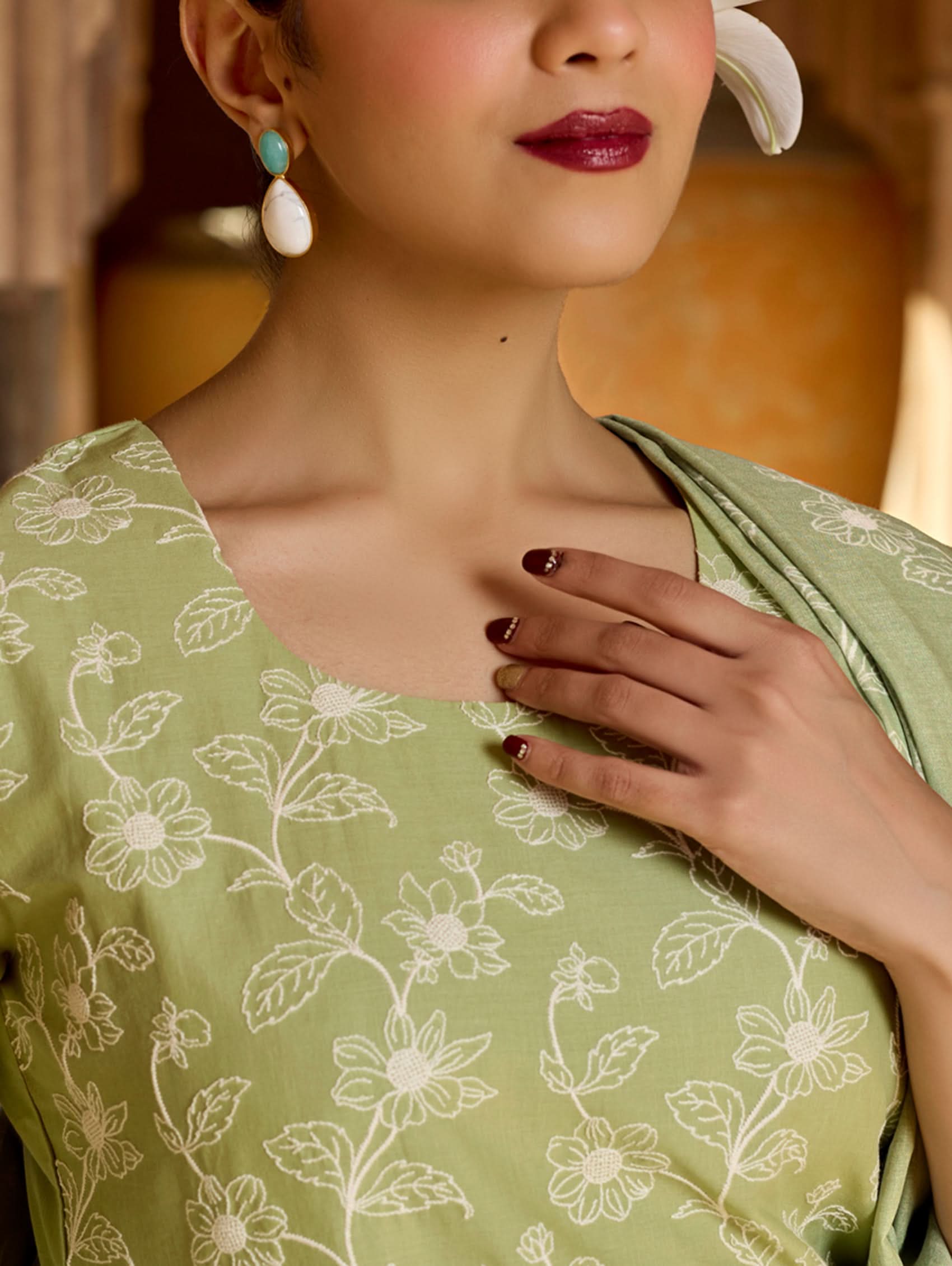 Woman wearing a green saree with floral patterns.