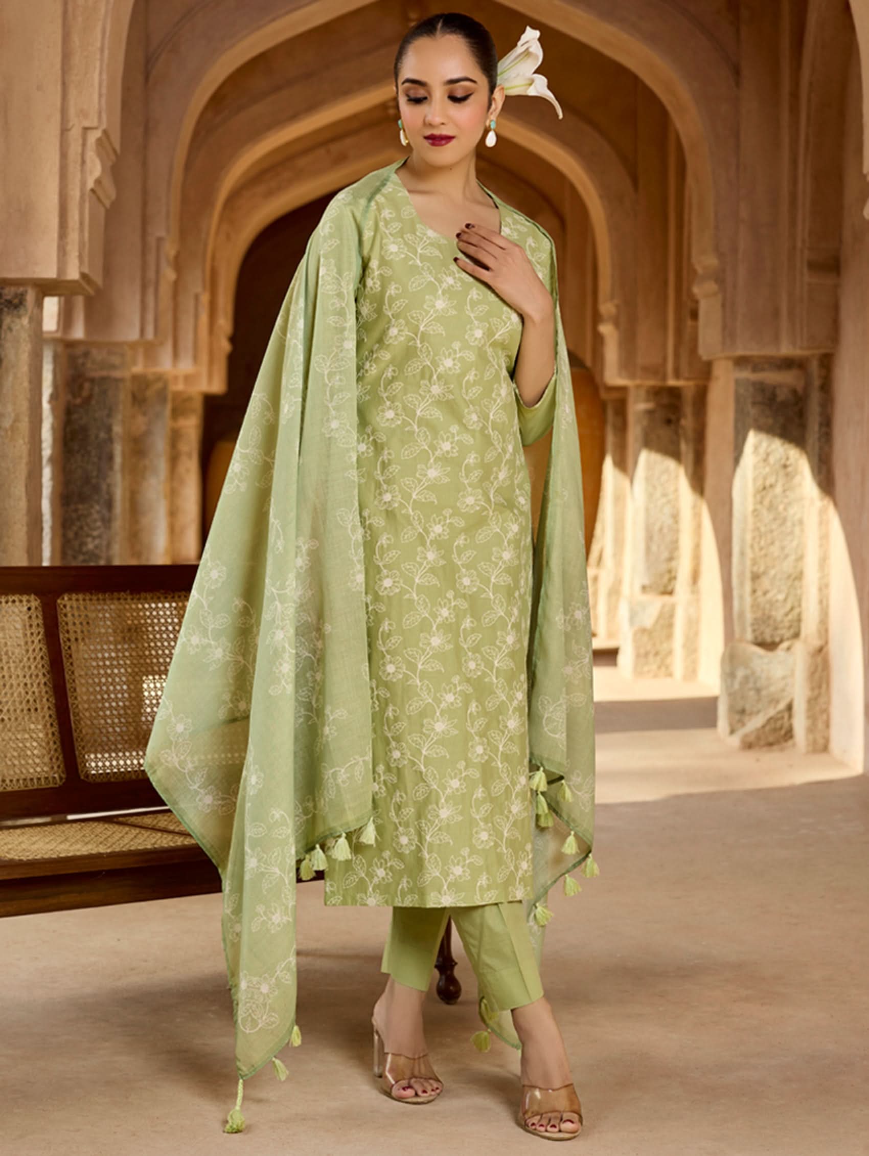 Woman in a light green traditional outfit with a dupatta in a historical setting.