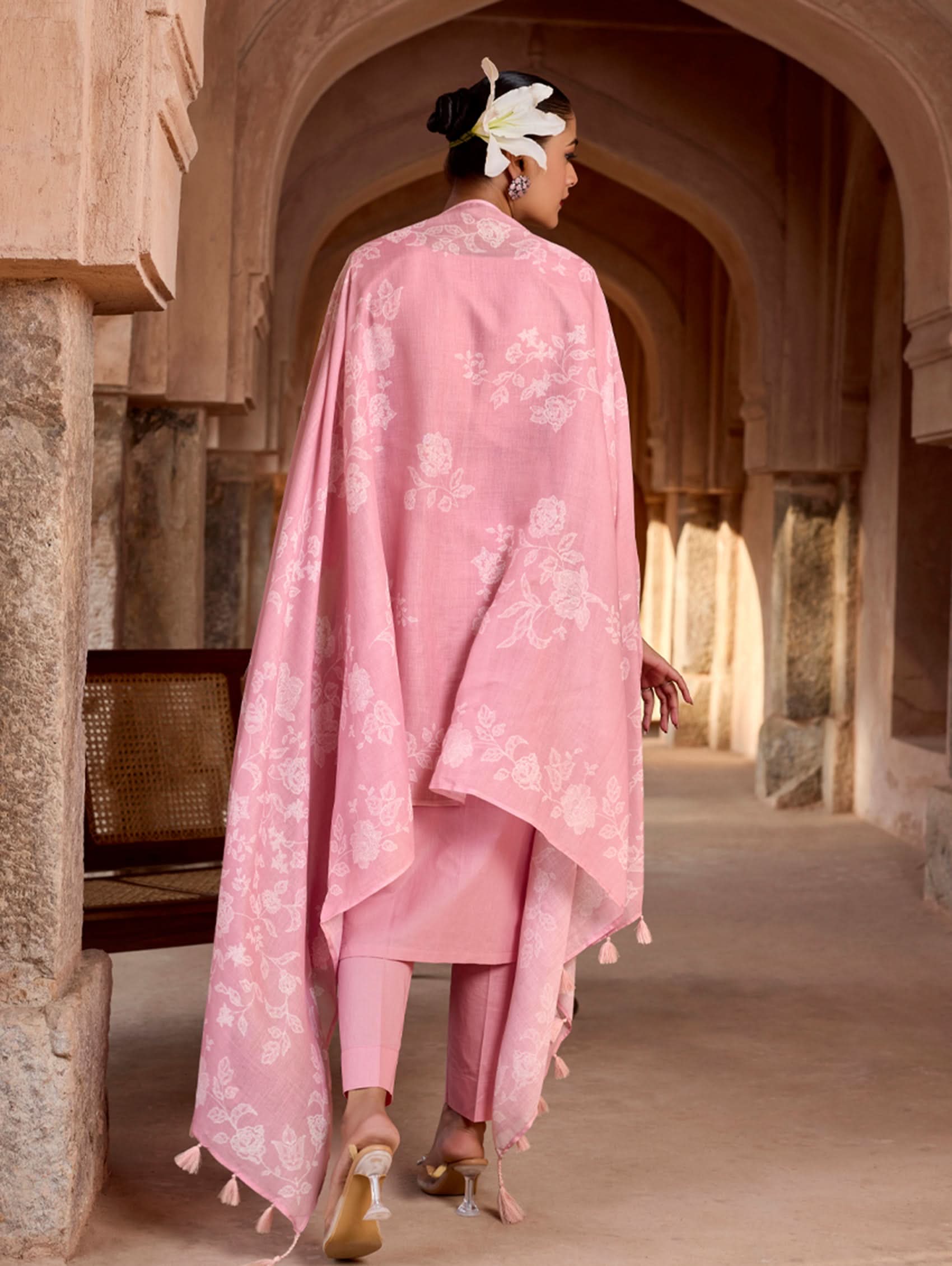 Person wearing a pink traditional outfit in an archway.