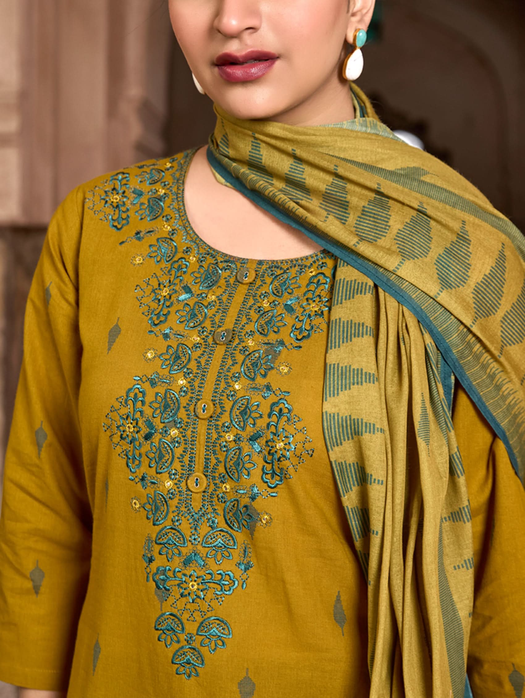 Woman wearing a mustard yellow dress with intricate embroidery and a matching shawl.