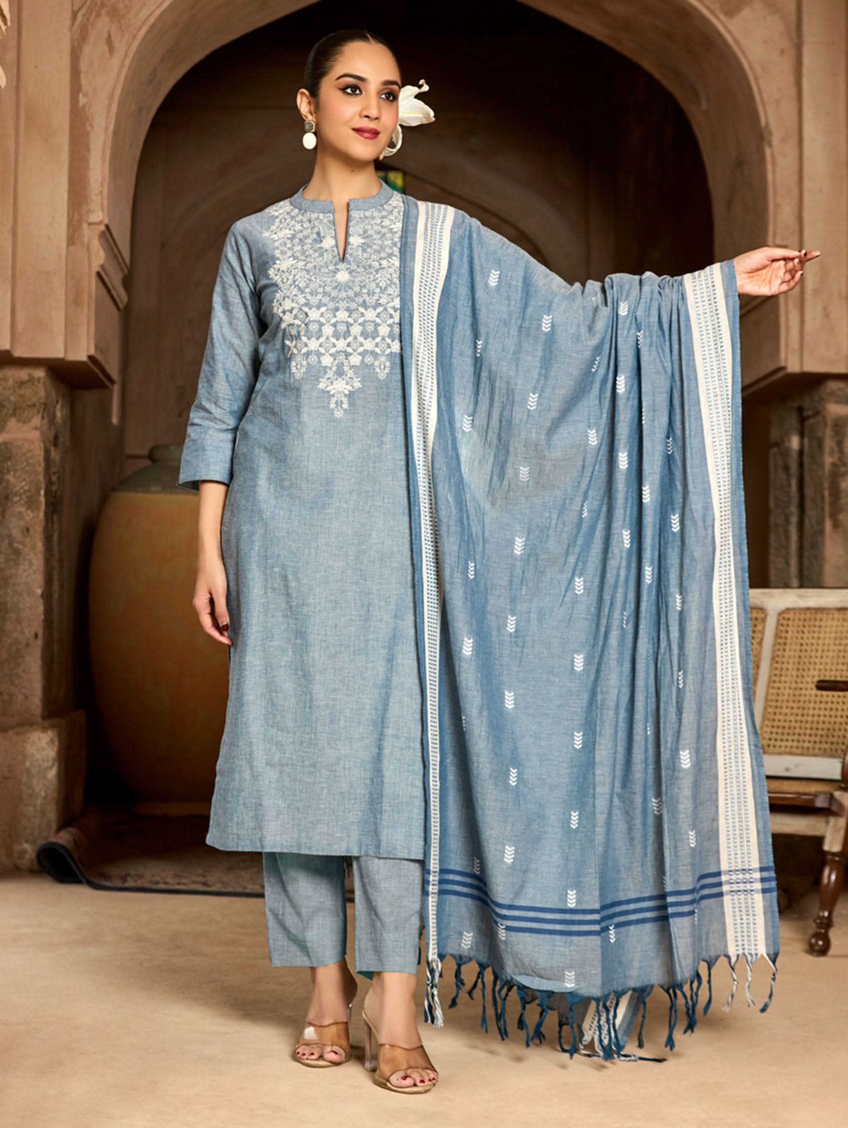 Woman in a blue traditional outfit with a dupatta in an archway.