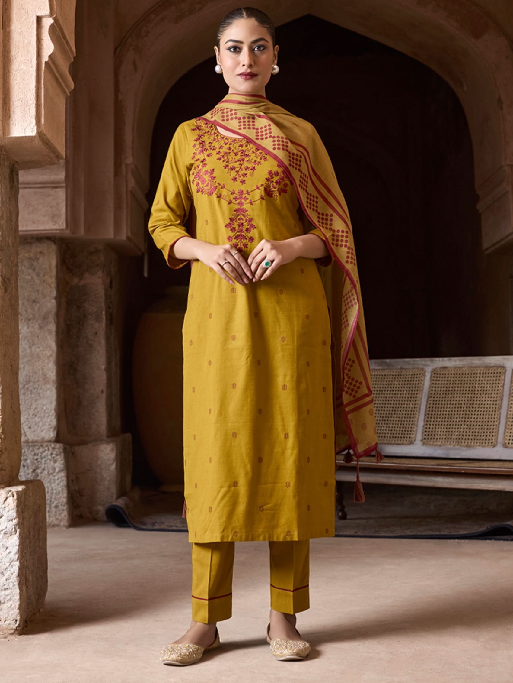 A model wearing a yellow kurta with red embroidery, paired with matching pants, and a printed dupatta.