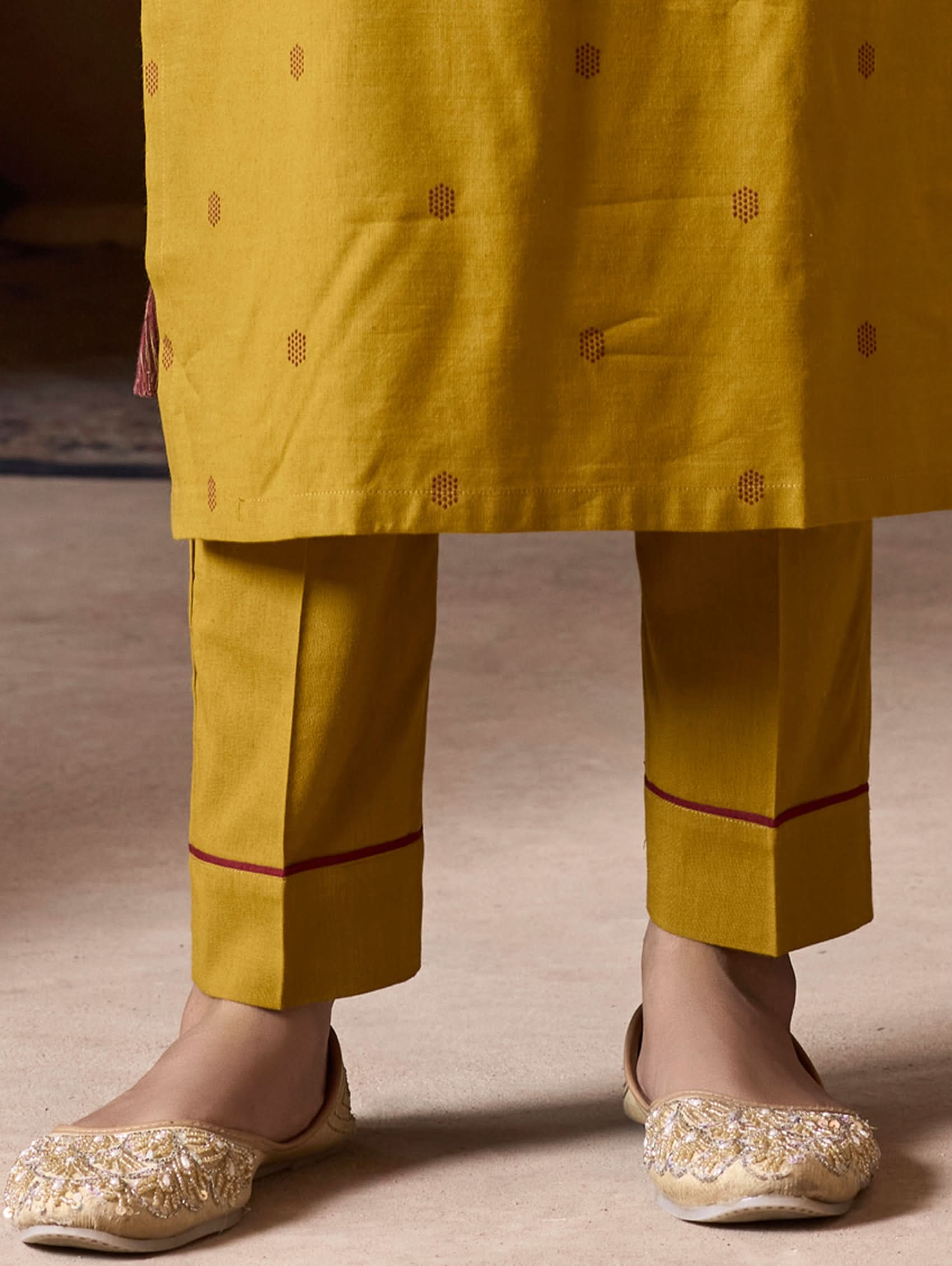Yellow traditional outfit with embroidered details on a neutral background