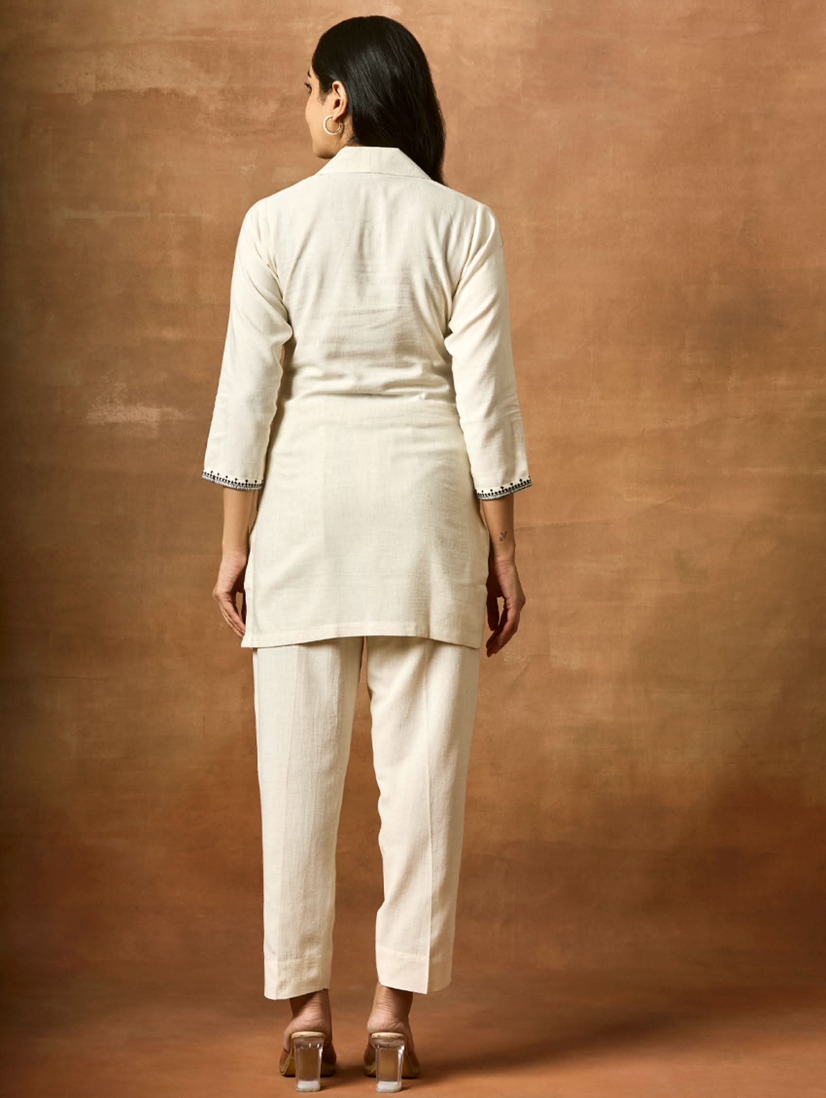 Person wearing a beige suit against a brown background