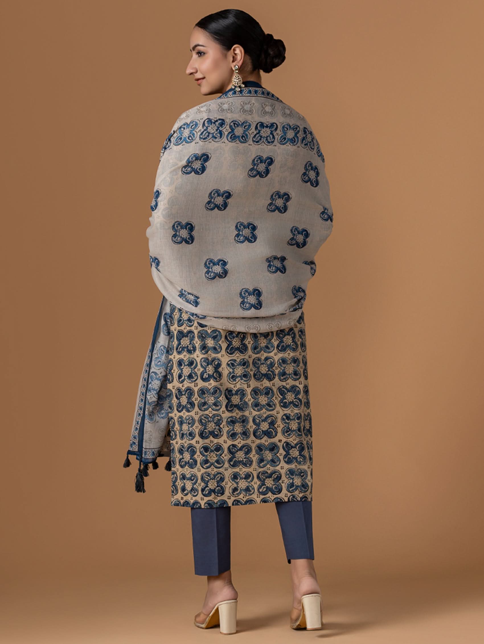 Woman wearing a patterned shawl and dress on a brown background
