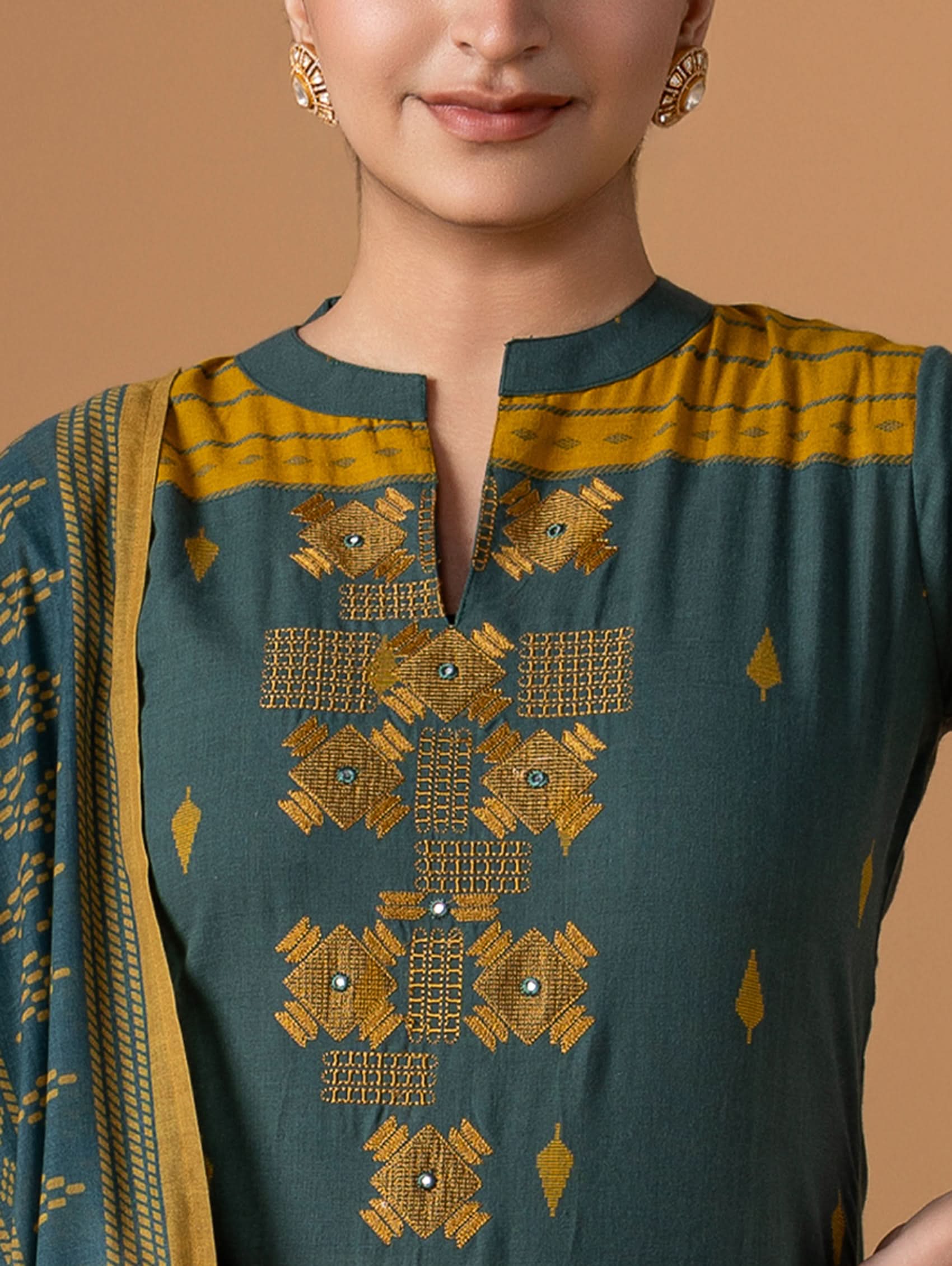 Green and yellow embroidered traditional outfit with a plain background