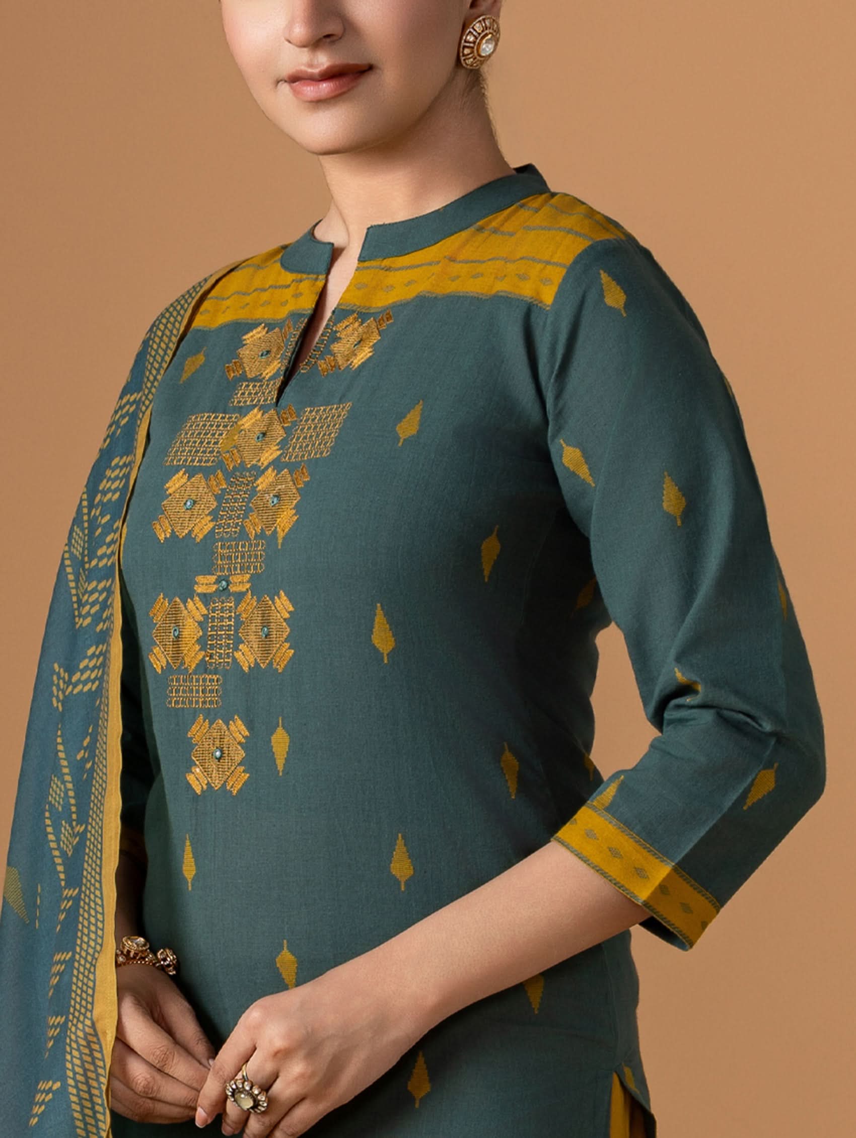 Green and gold traditional outfit with intricate patterns on a brown background