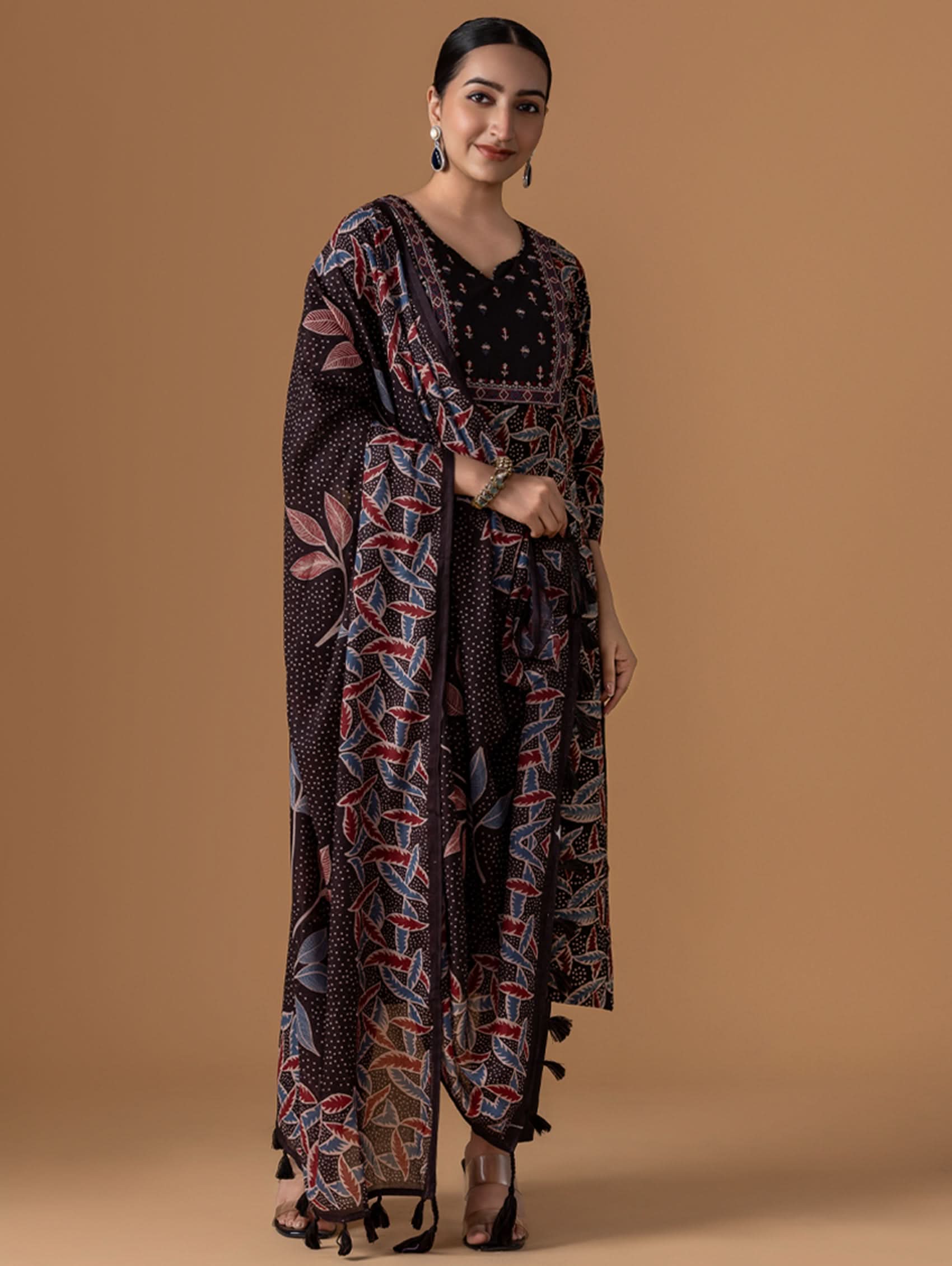 A woman modeling a traditional Indian suit set with geometric ajrakh patterns, consisting of a kurta, pants, and a dupatta.