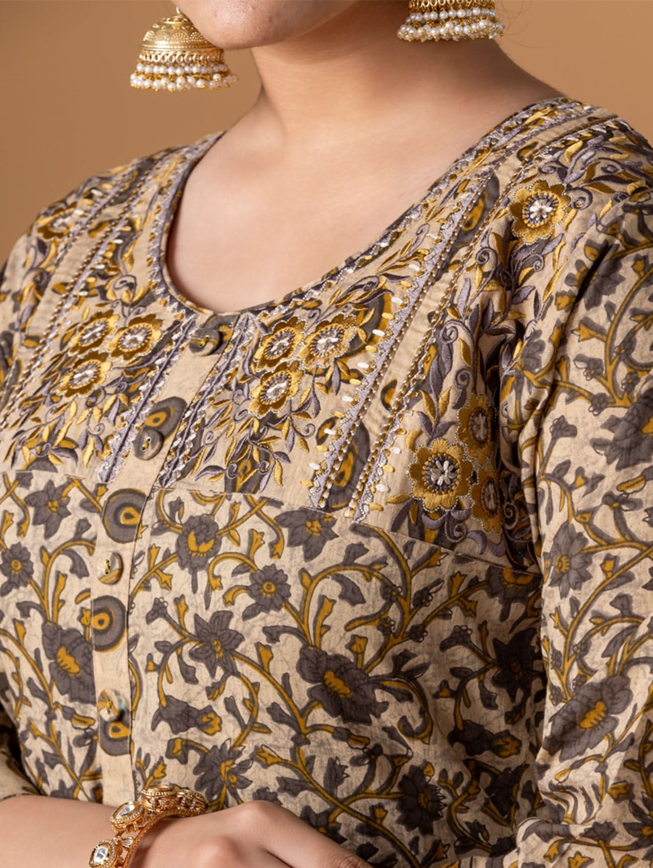 Close-up of a person wearing a patterned outfit with gold and brown colors.