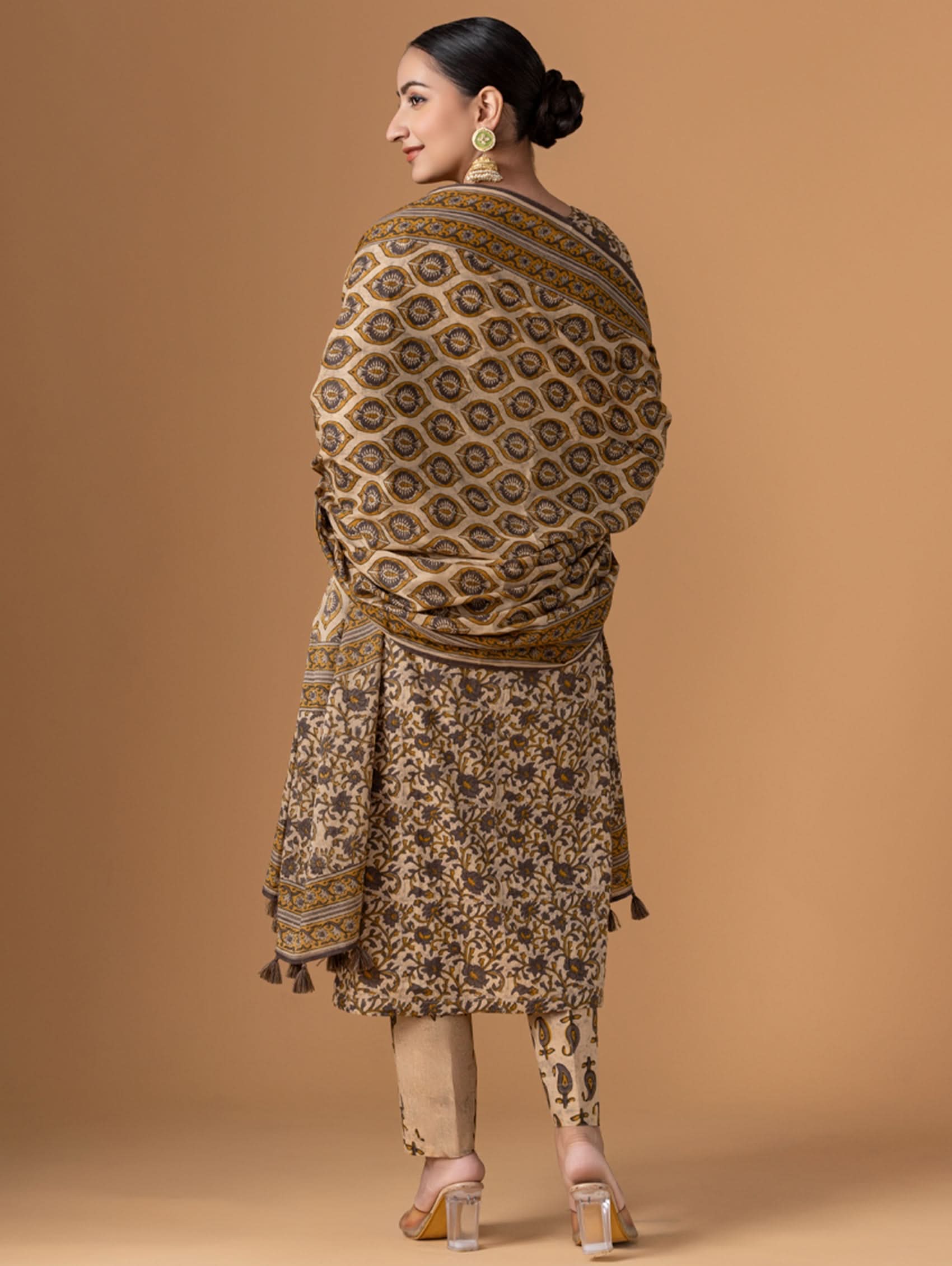 Woman wearing a patterned outfit with a shawl on a beige background