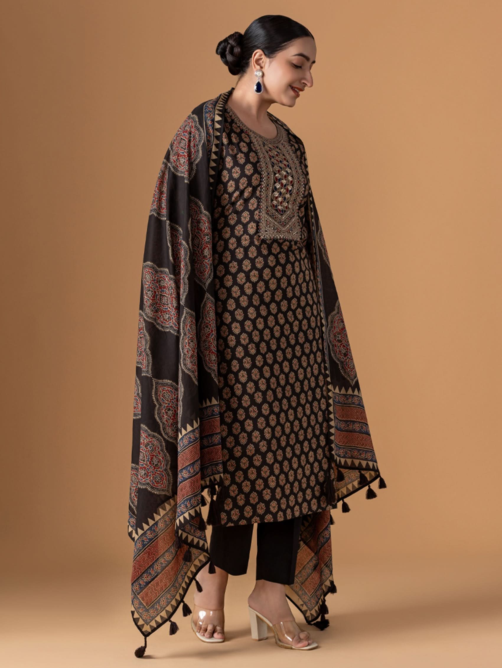Woman wearing a traditional outfit with a patterned shawl on a beige background