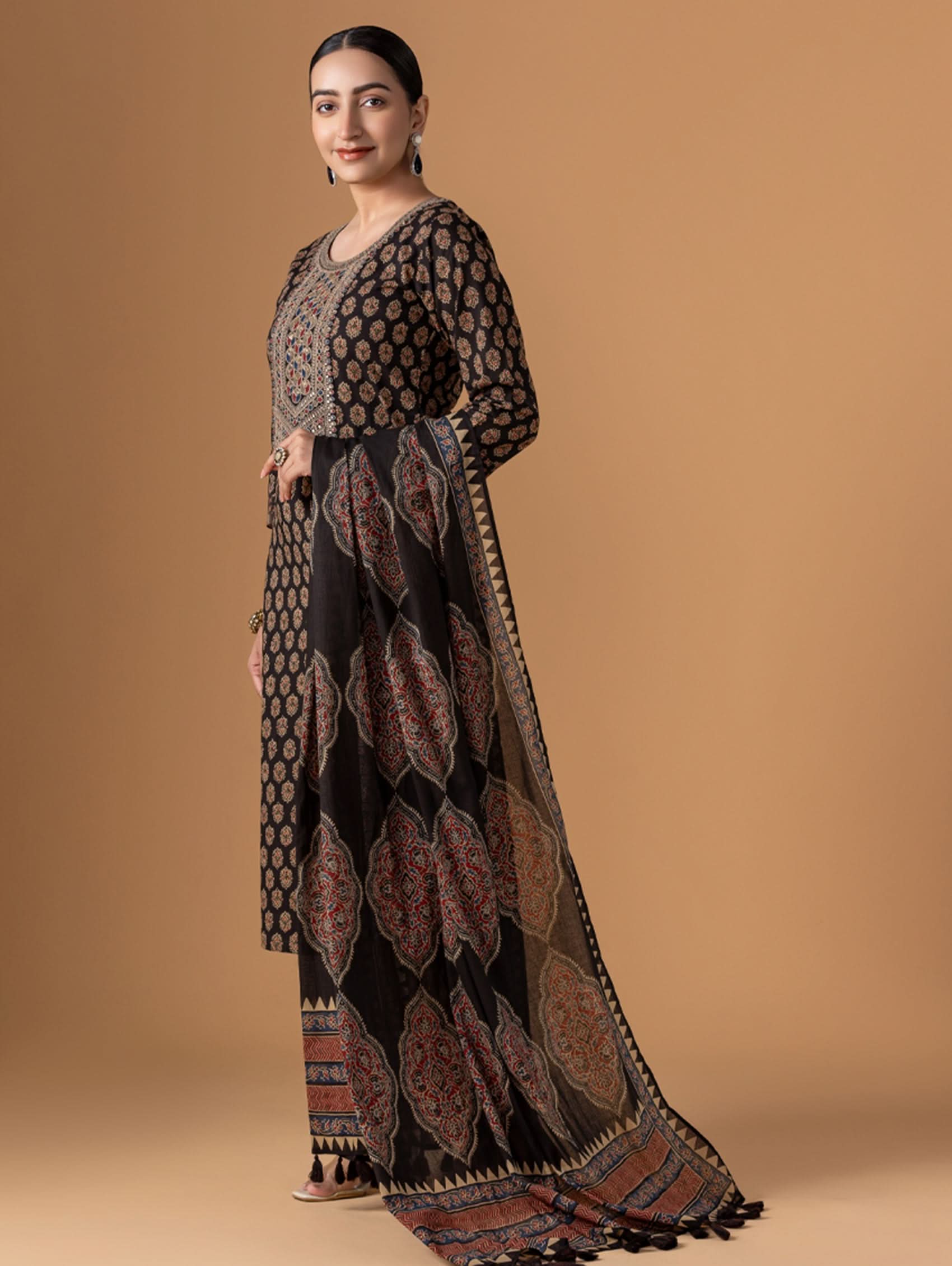Woman wearing a long, patterned dress against a beige background