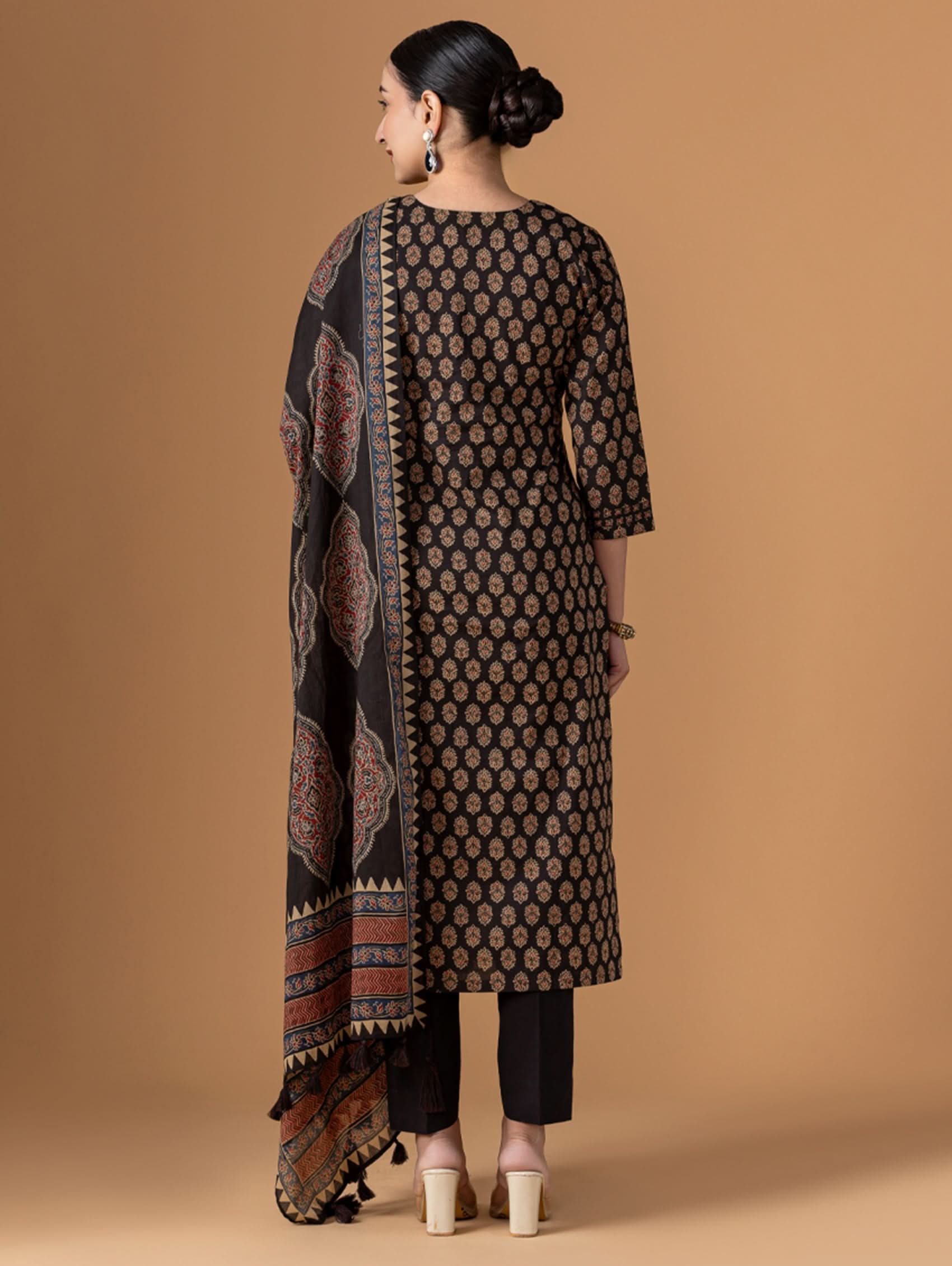 Woman wearing a patterned kurta with a long scarf against a beige background