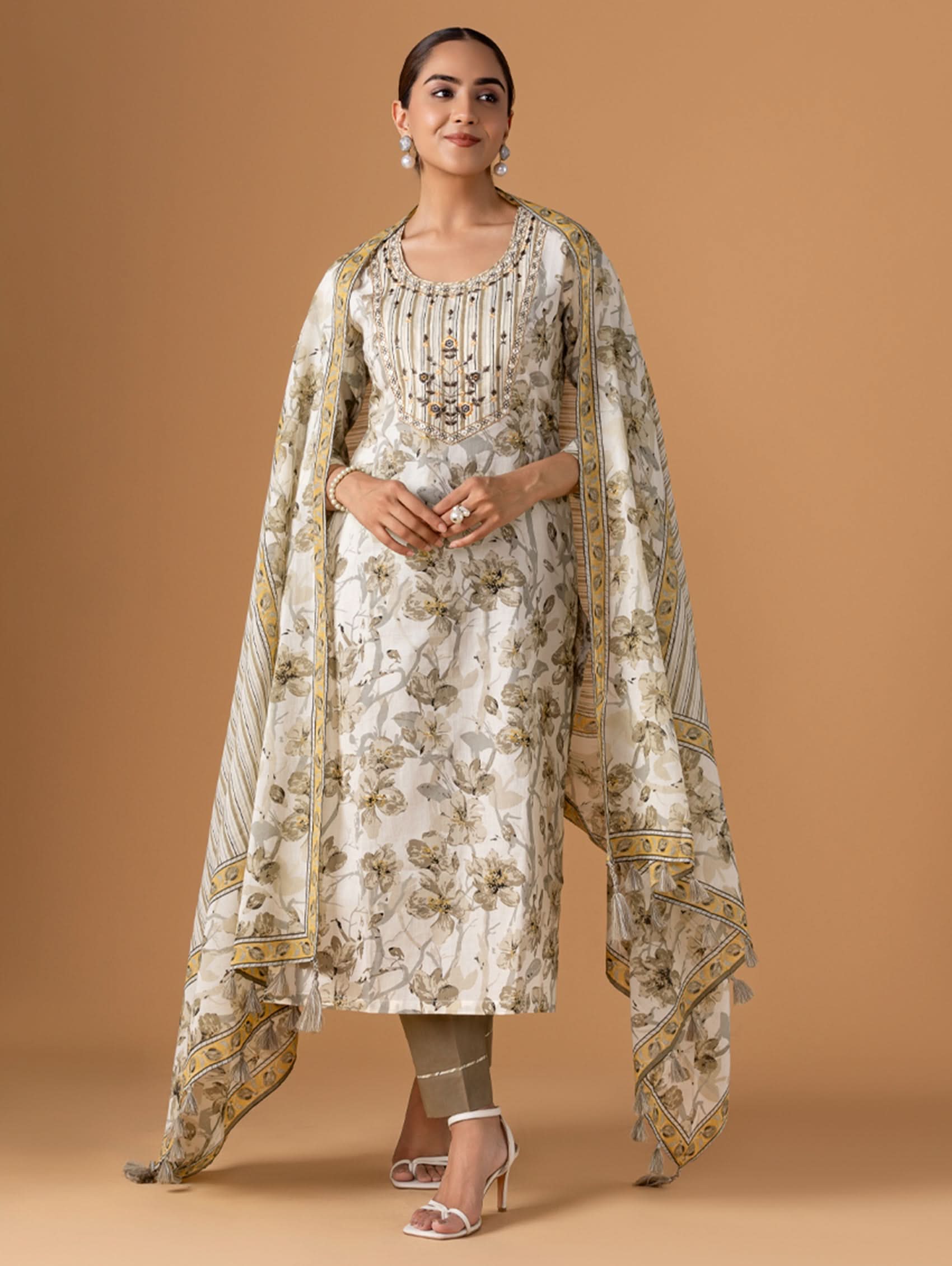 Woman wearing a floral dress with a matching dupatta on a brown background