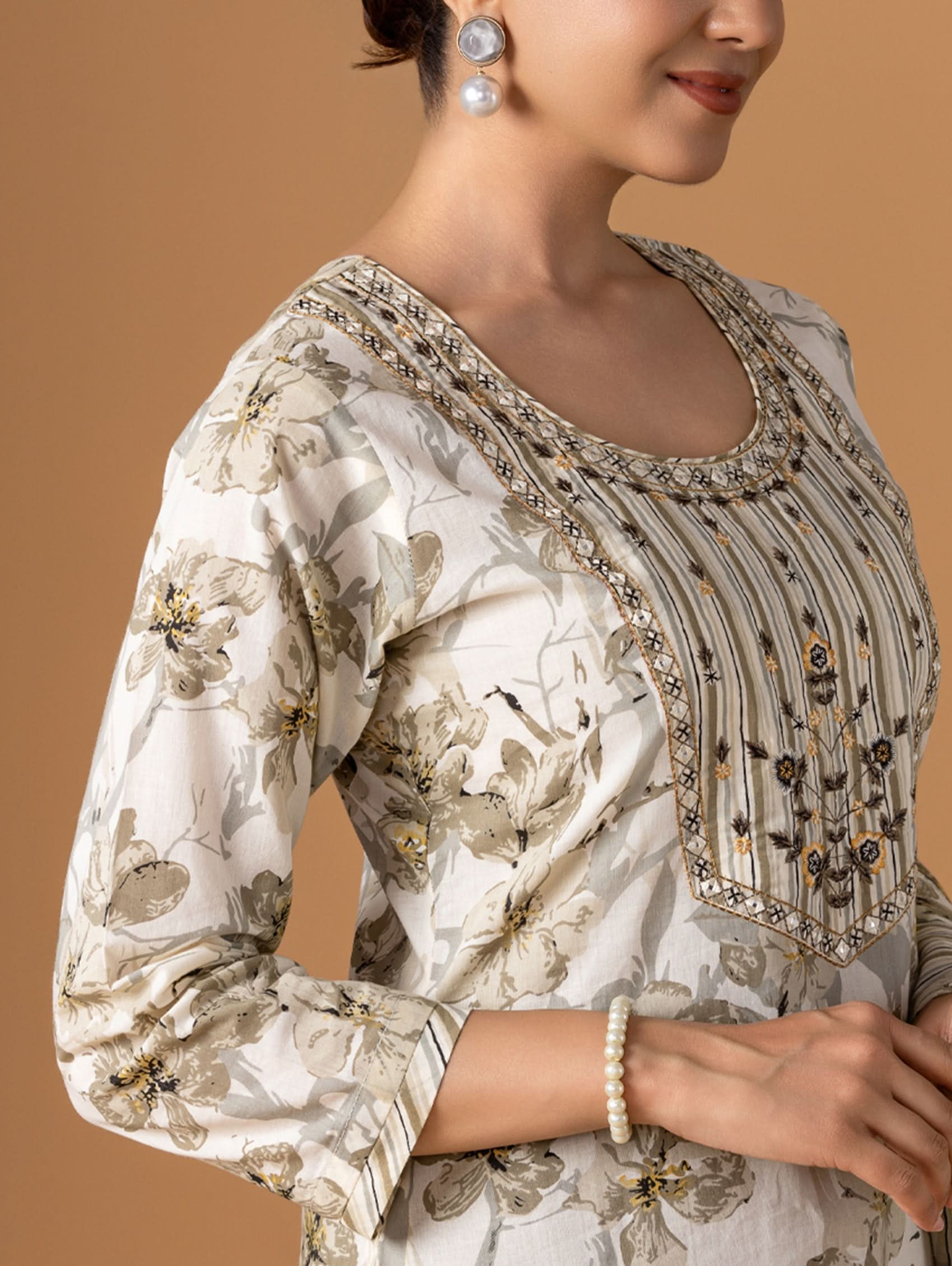 Woman wearing a floral blouse with intricate embroidery on a beige background