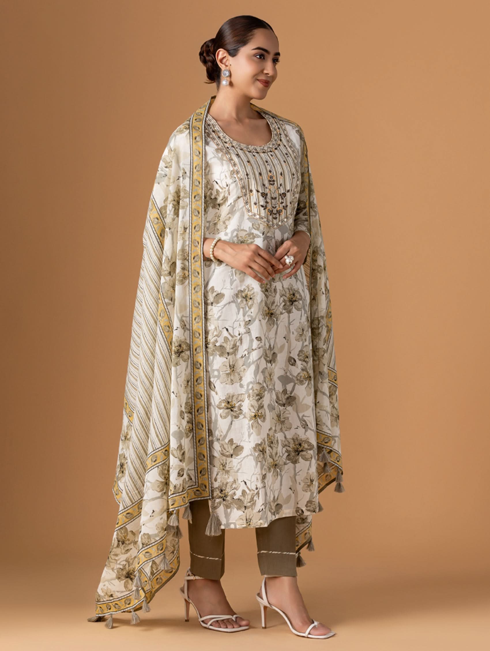 Woman wearing a floral kurta with a matching dupatta on a brown background