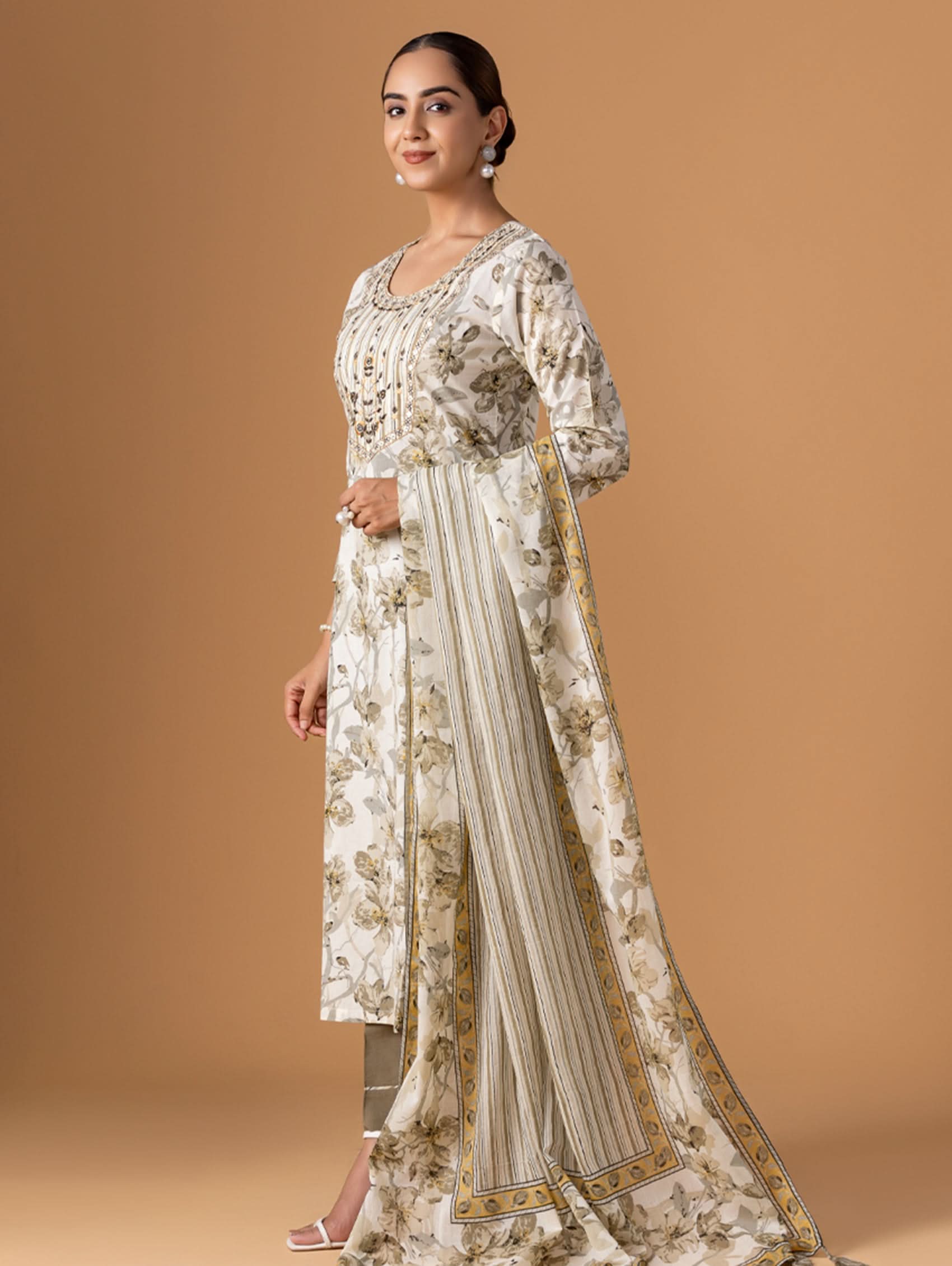 Woman wearing a floral kurta with a matching dupatta on a beige background