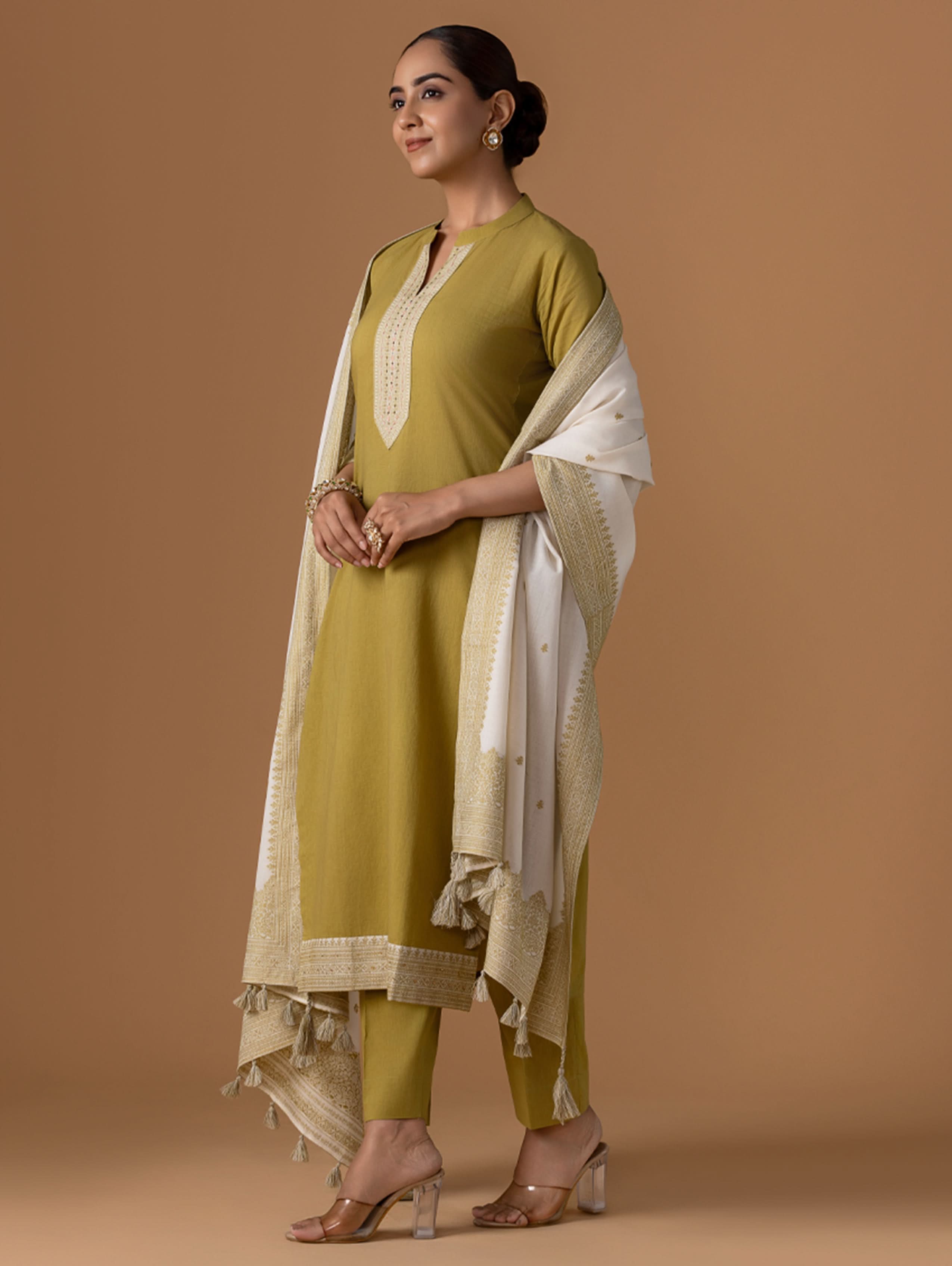 Woman in green traditional outfit with white dupatta on a brown background