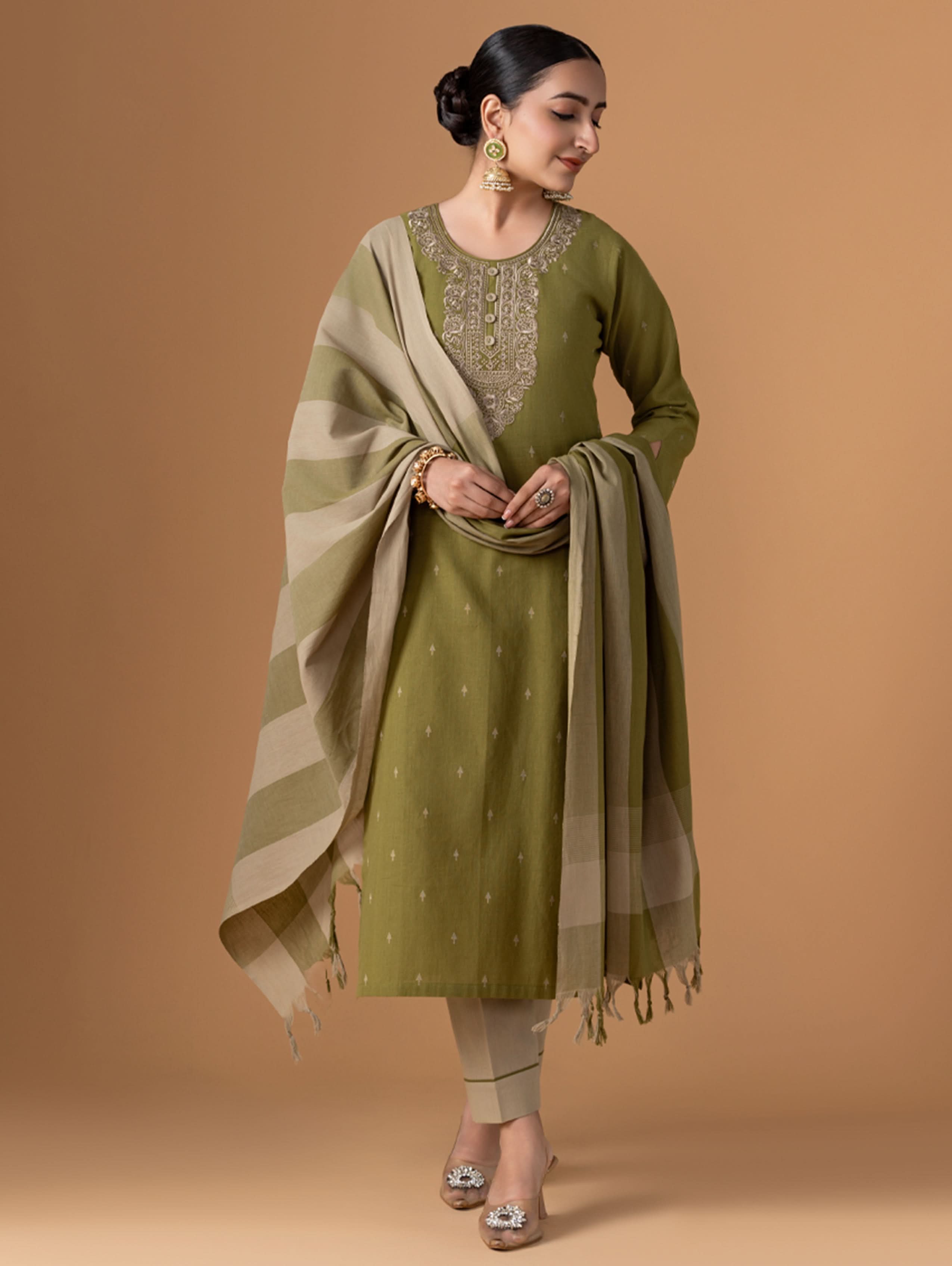 A woman modeling a green Jamdani pure cotton suit set with embroidery on the kurta, wearing straight pants and a dupatta.
