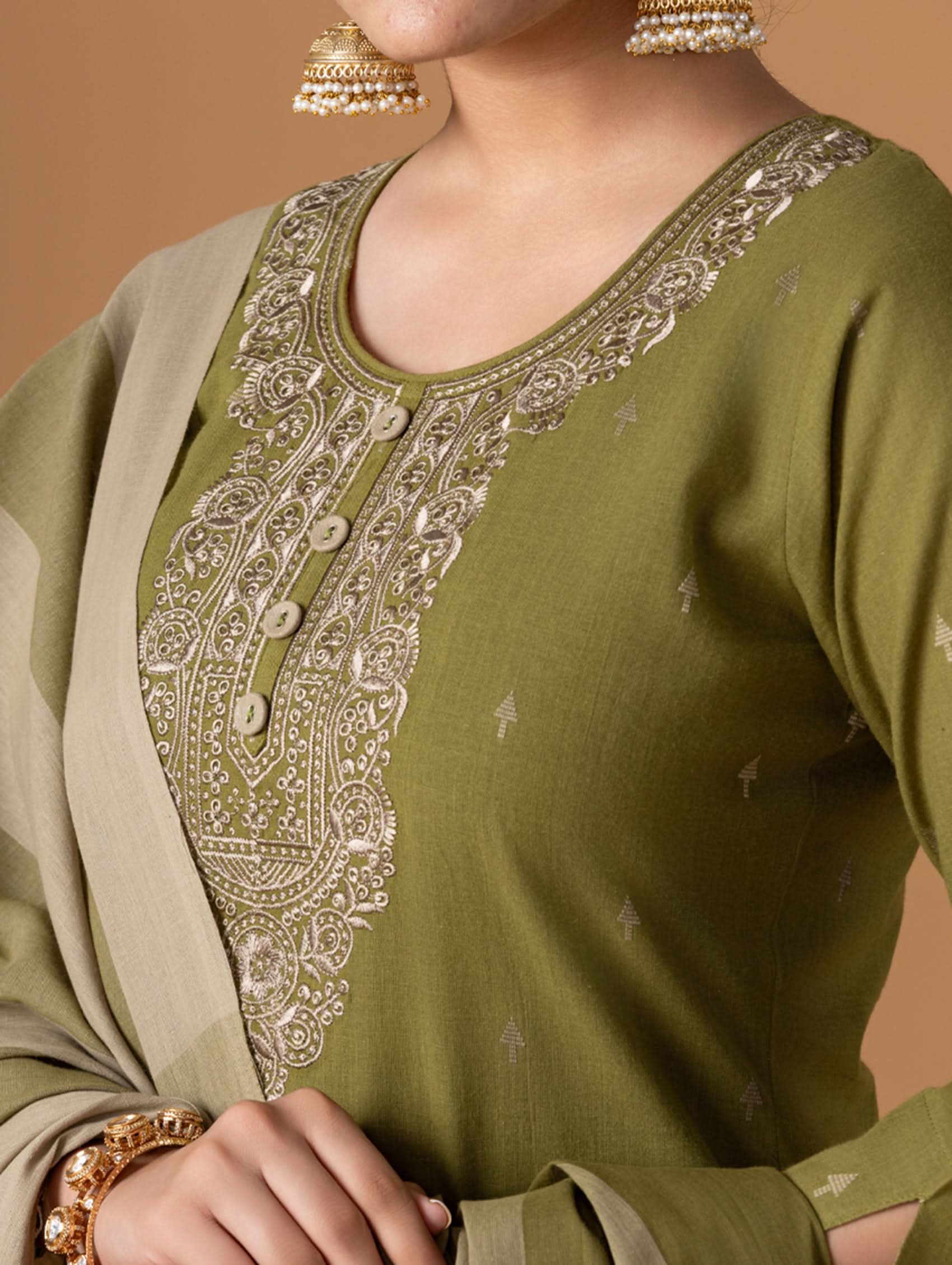 Green embroidered traditional outfit with beige dupatta on a brown background