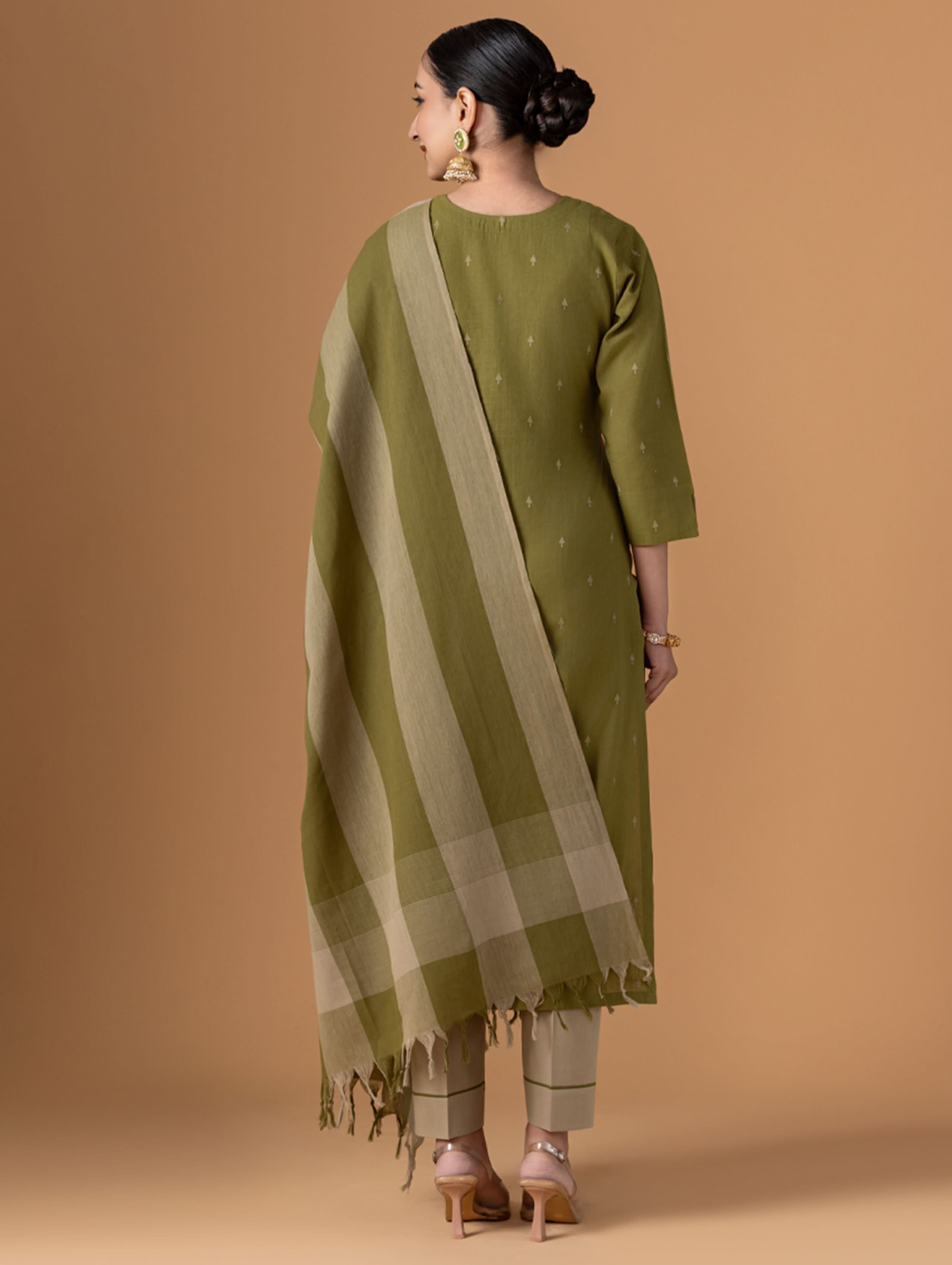 Woman wearing a green kurta with a matching dupatta on a beige background