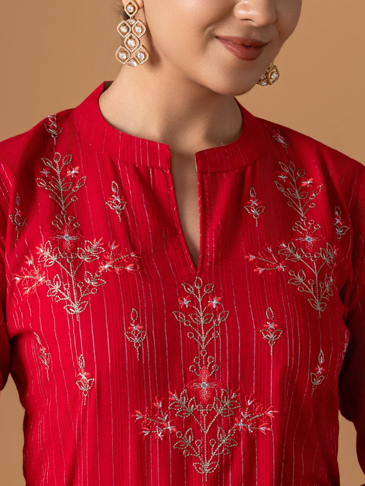 Red embroidered blouse with intricate patterns on a beige background