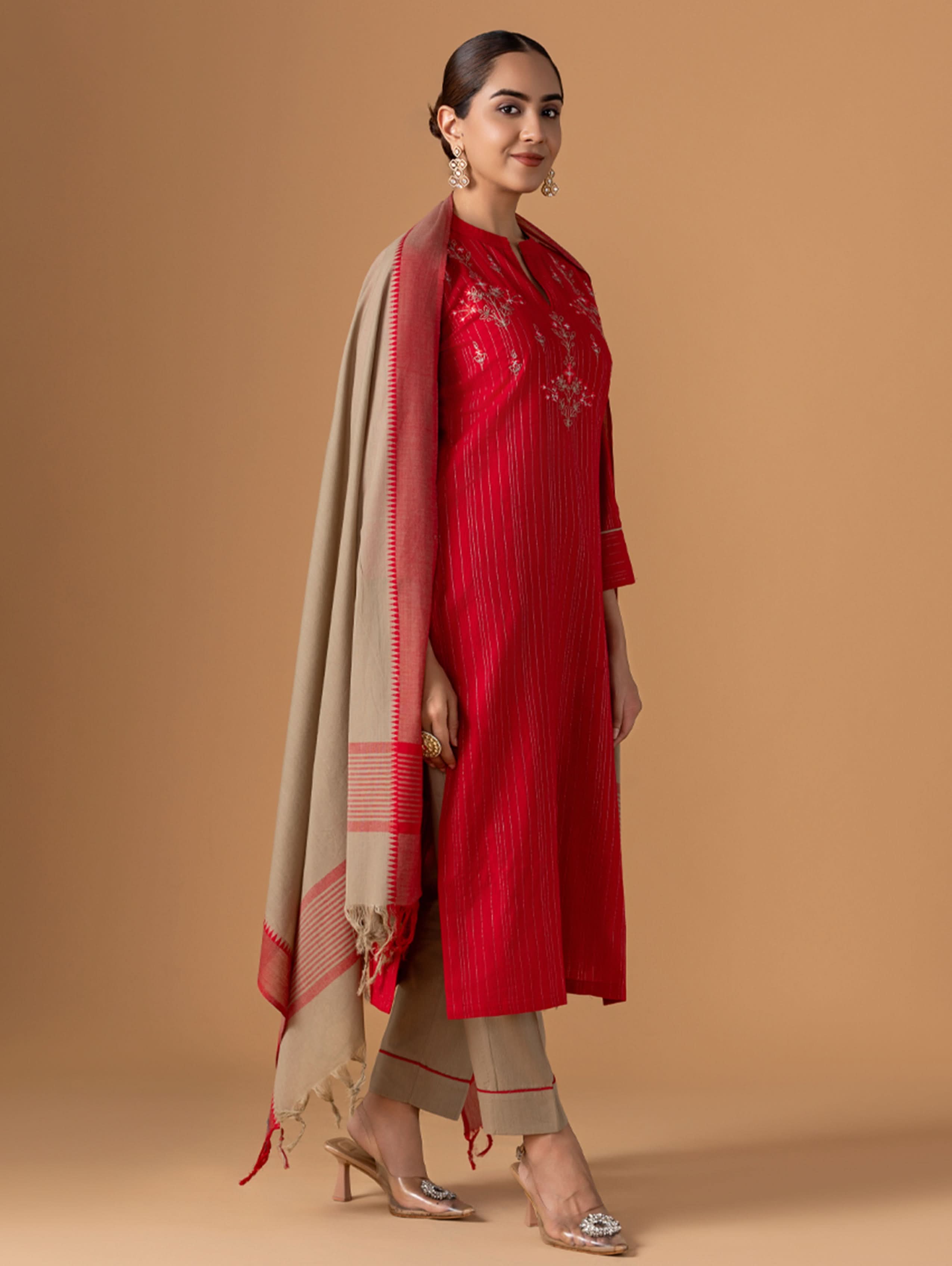 Woman wearing a red outfit with a beige scarf against a brown background