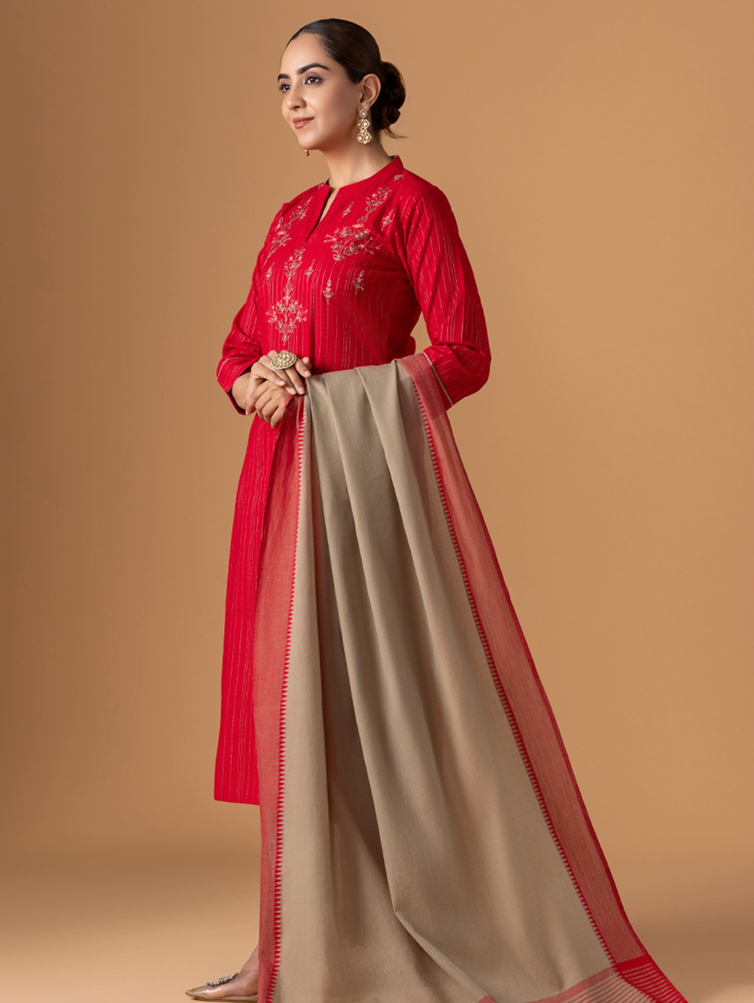 Woman wearing a red and beige traditional outfit on a brown background