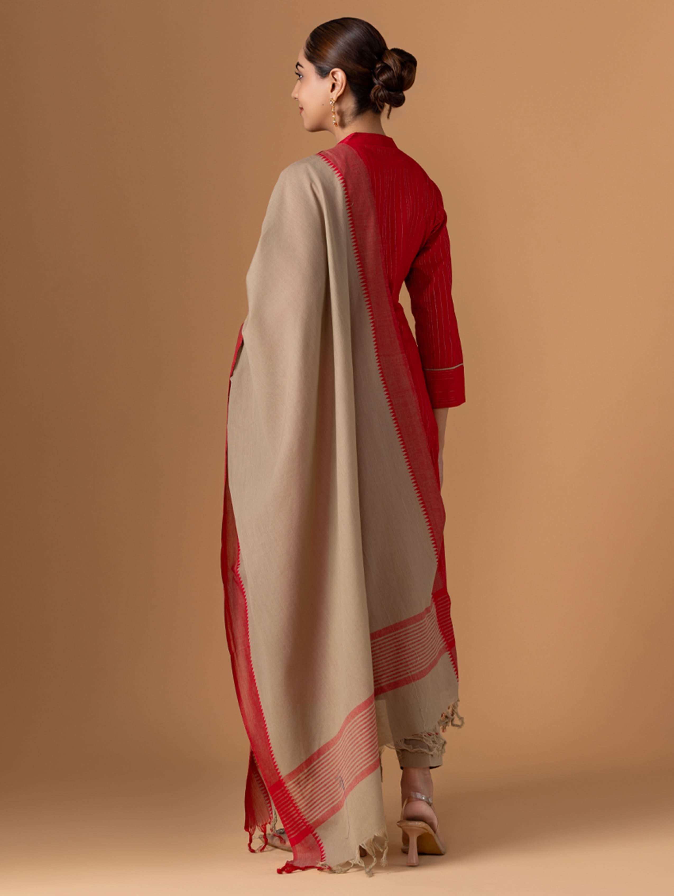 Woman wearing a beige and red traditional outfit on a brown background