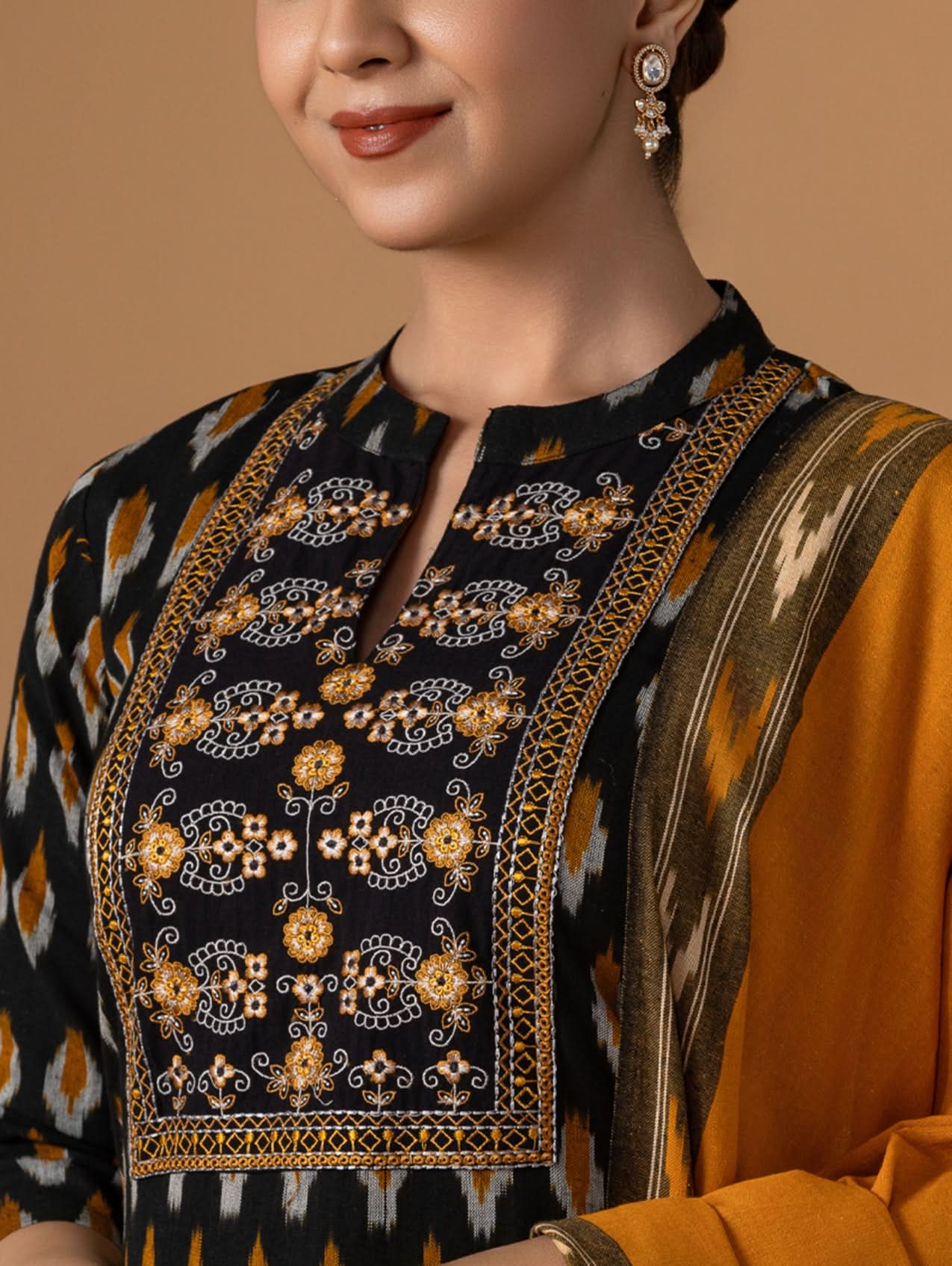Woman wearing a traditional outfit with intricate embroidery on a brown background
