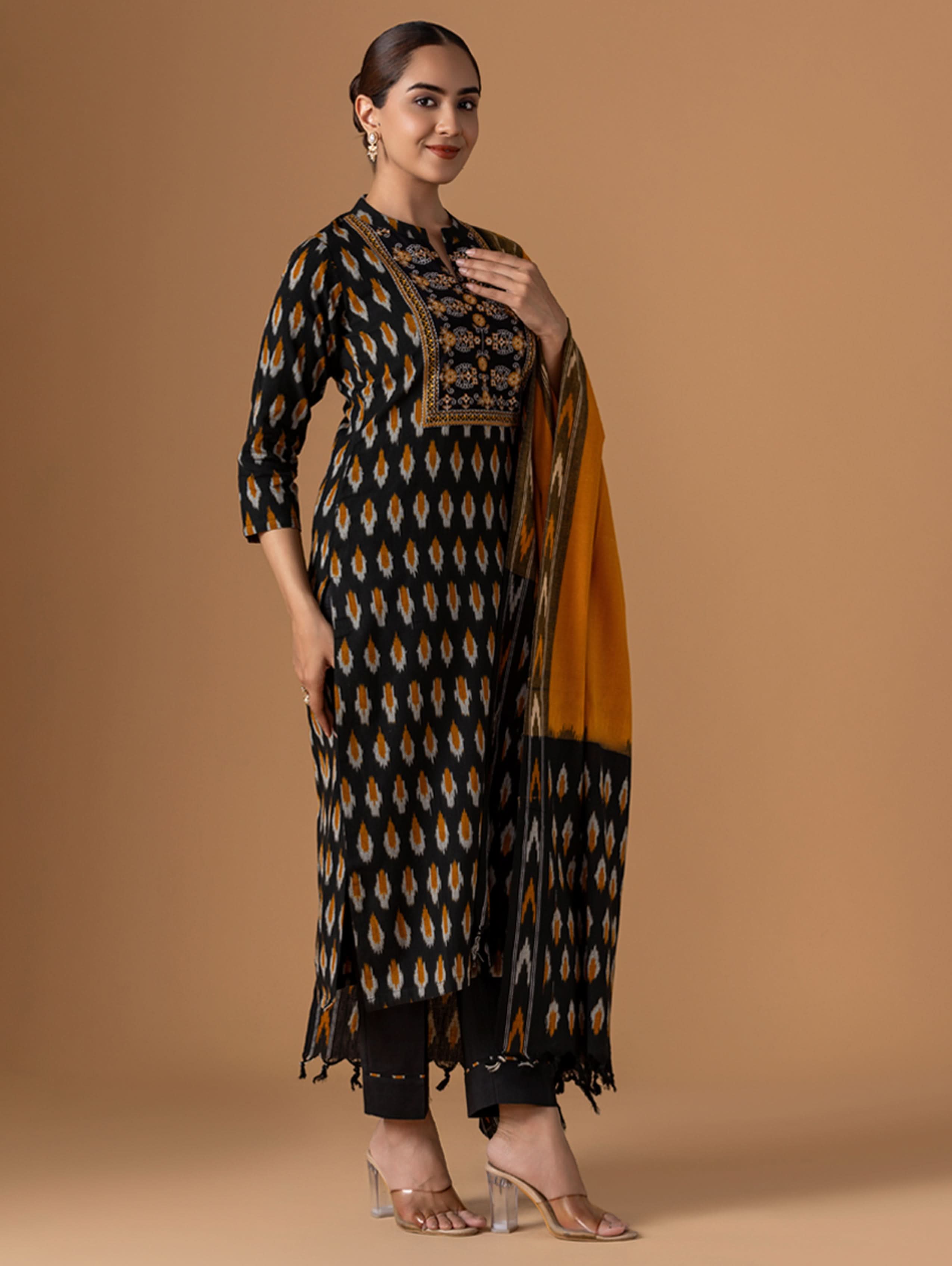 Woman wearing a patterned kurta with a drape against a beige background