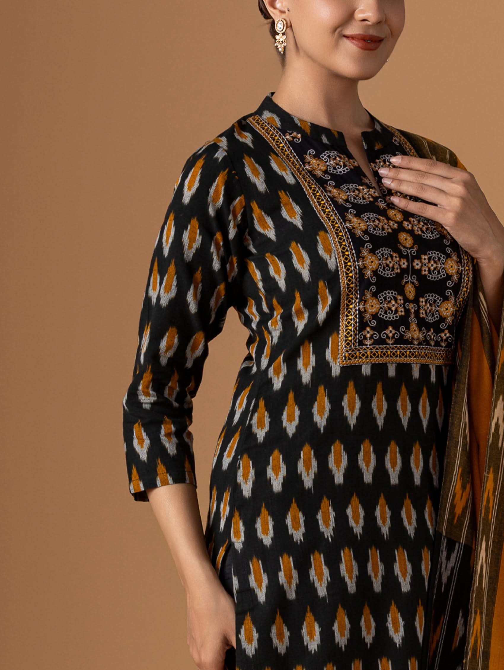 Woman wearing a black and gold patterned dress with a plain background